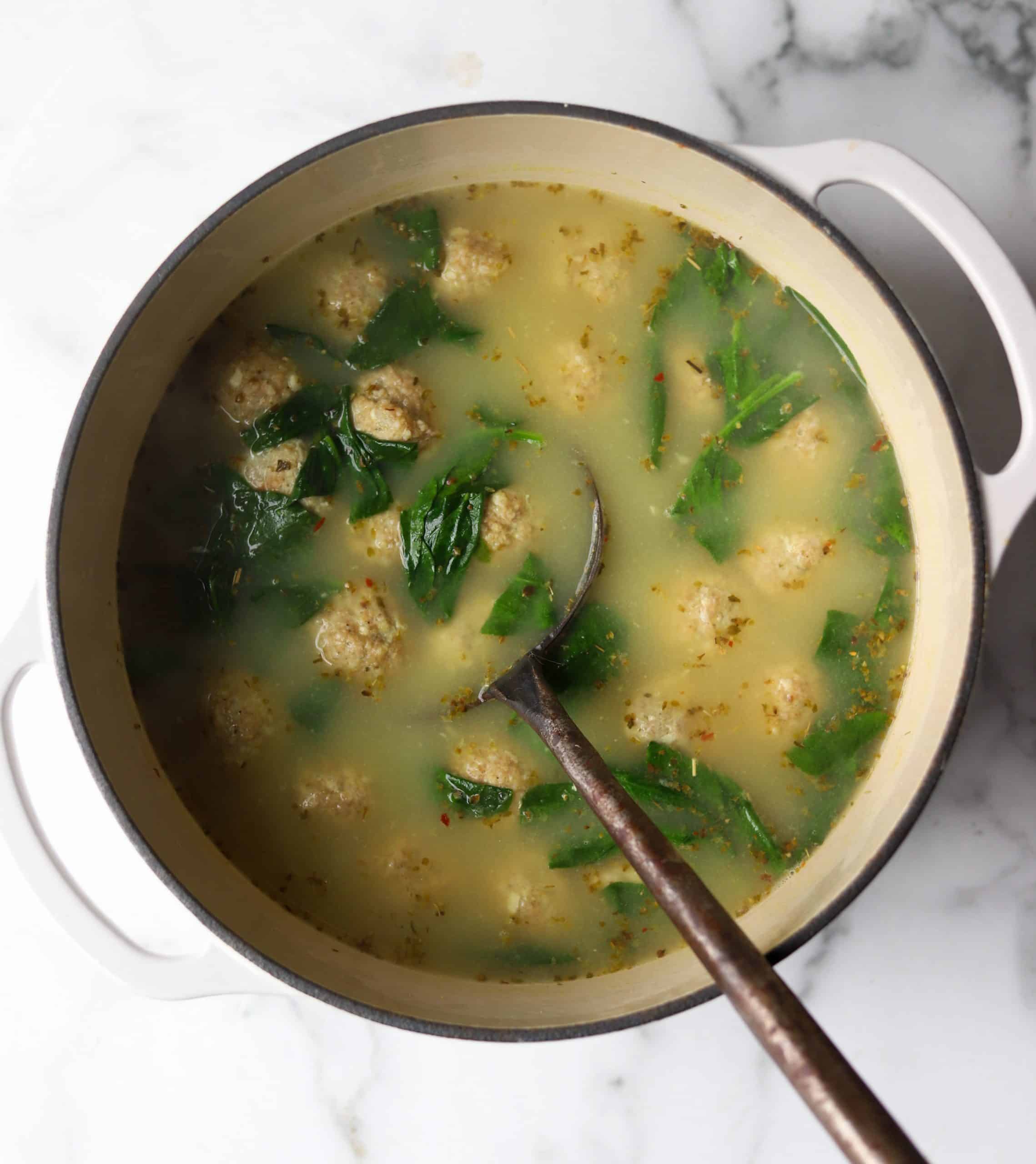 Italian wedding soup in a white bowl.