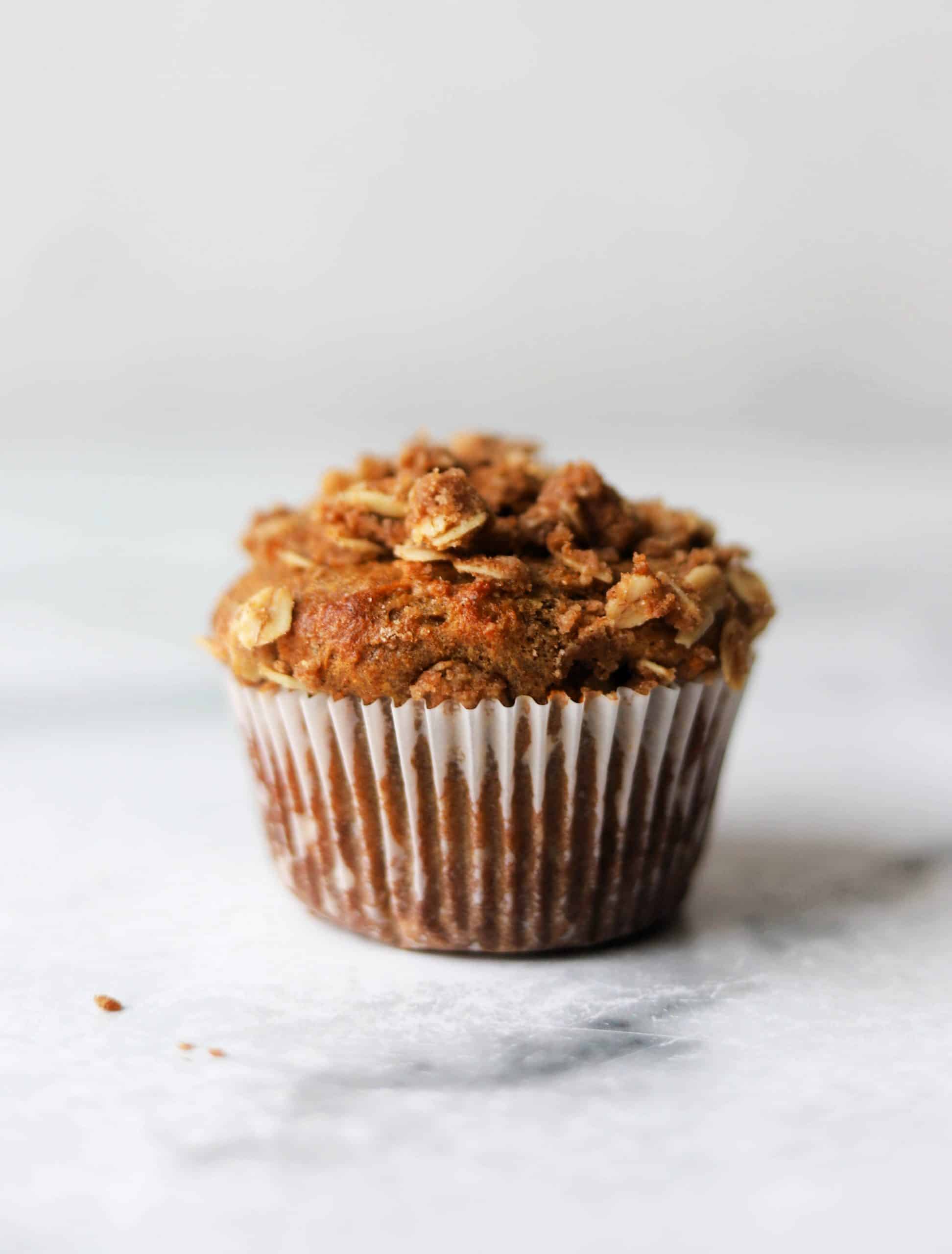 A single coffee cake muffin on a white marble board.