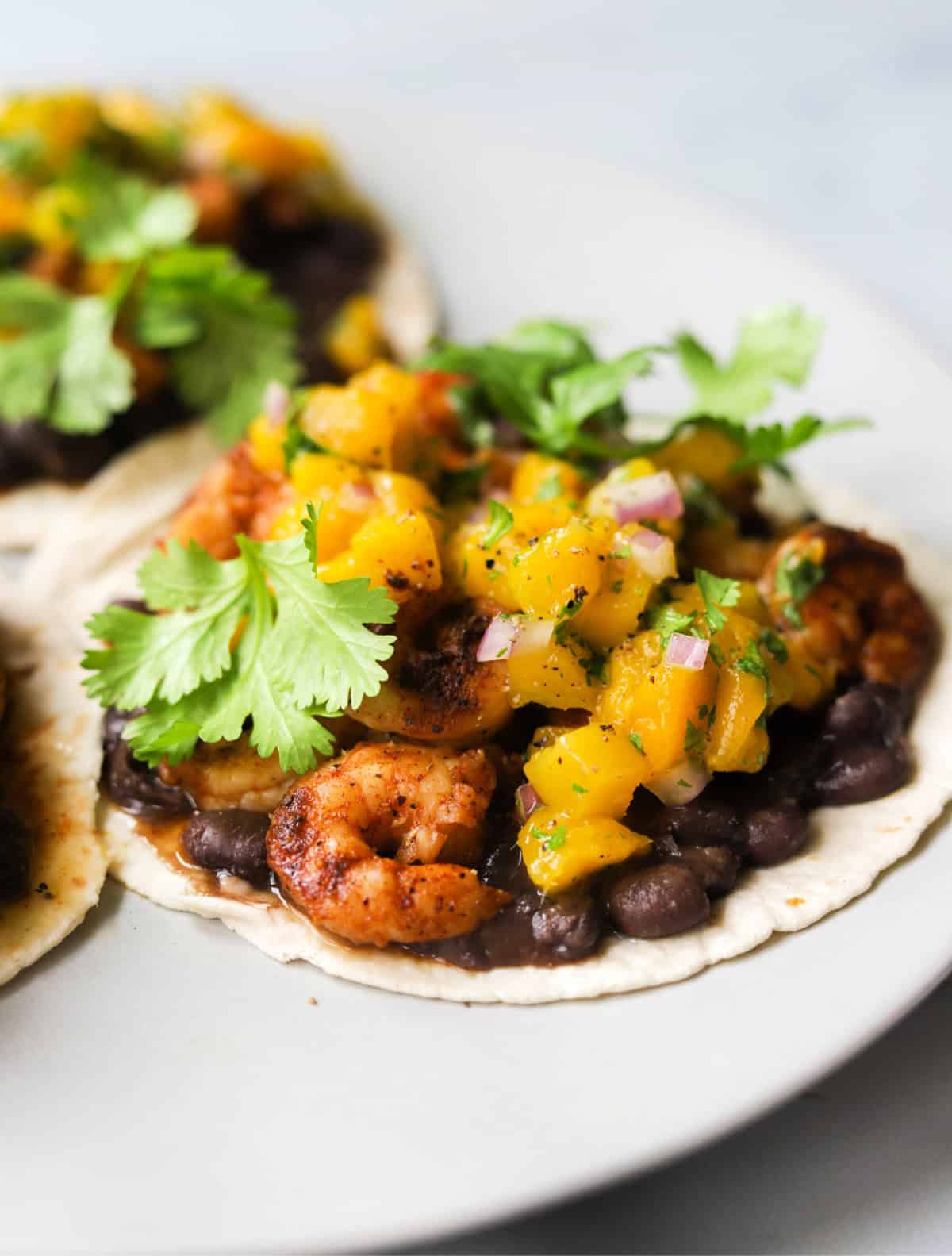 A front shot of shrimp tacos with mango salsa on top.