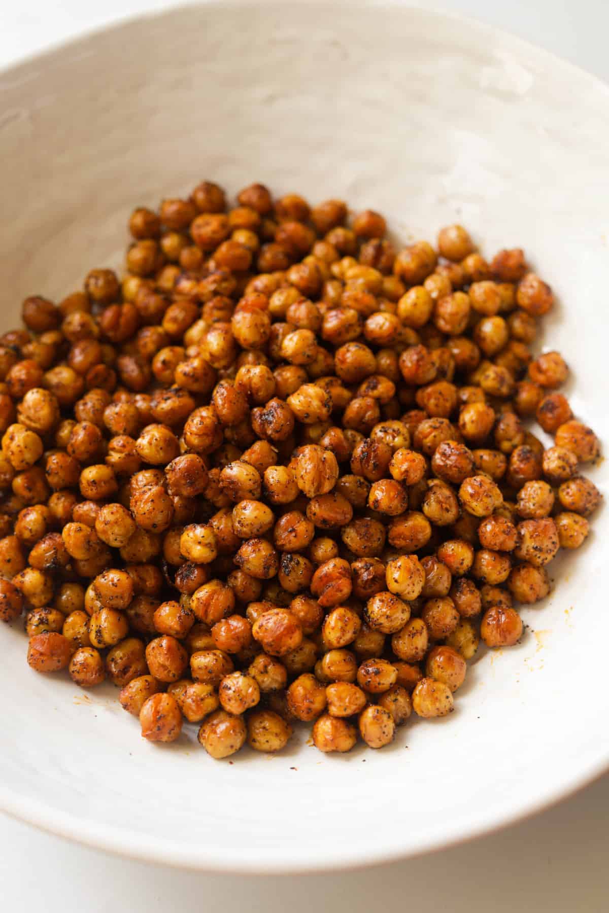 A side shot of a bowl of roasted chickpeas.