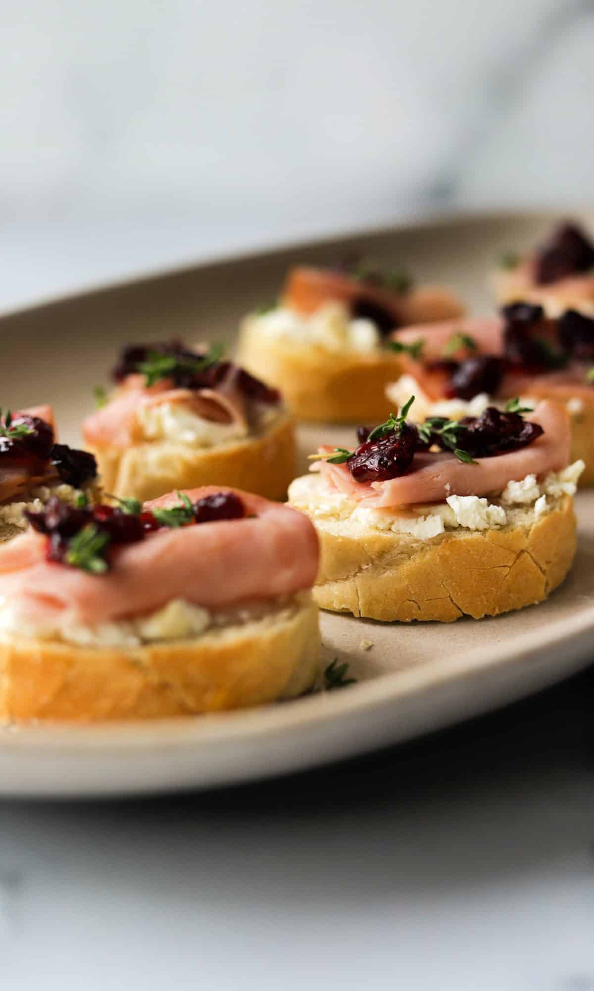 A side shot of a platter of goat cheese crostinis.