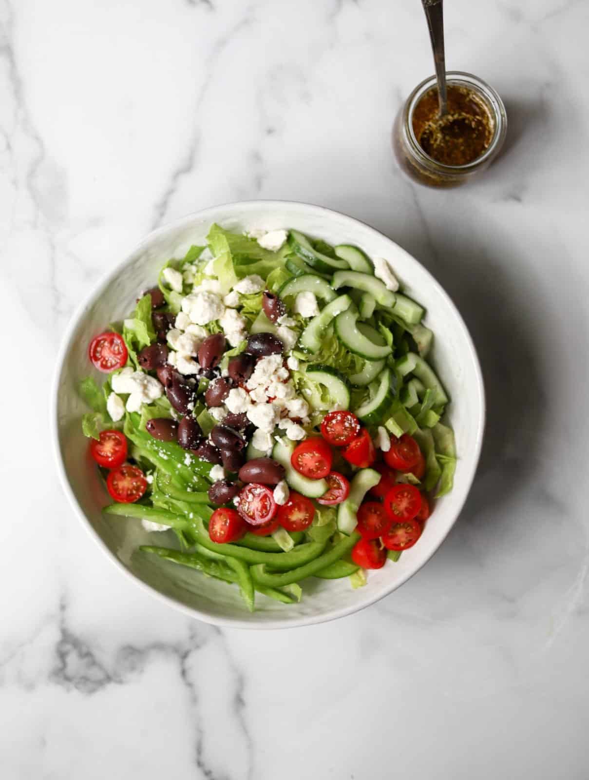 Greek salad in a white bowl.