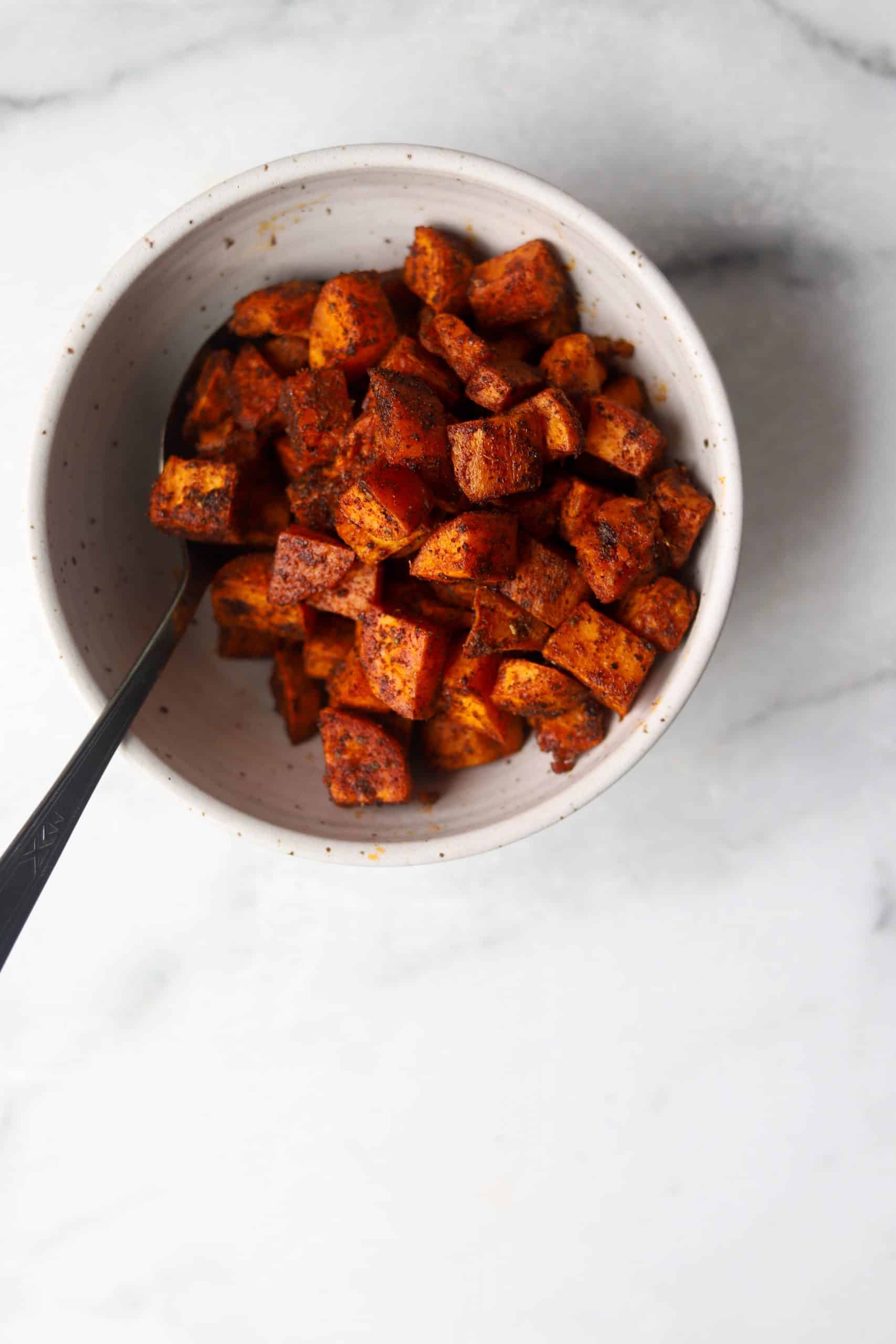 Roasted spiced sweet potatoes in a white bowl.