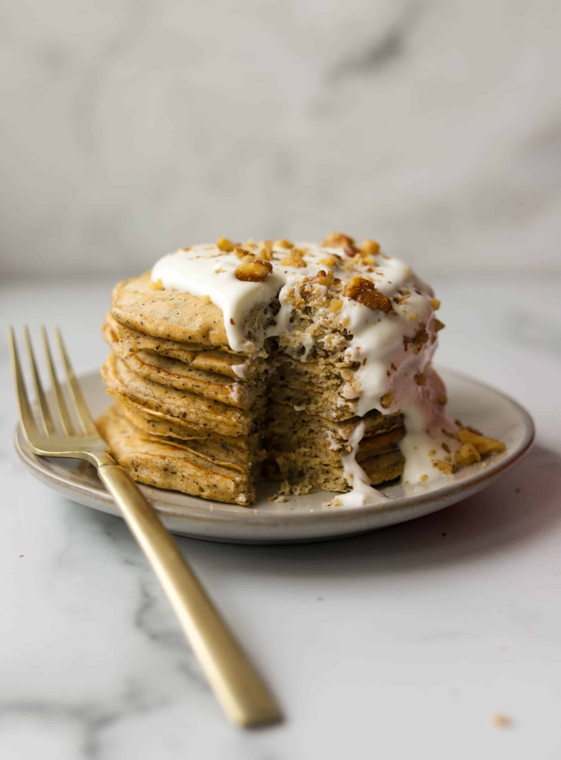 A side shot of a stack of walnut chai pancakes with a bite missing.
