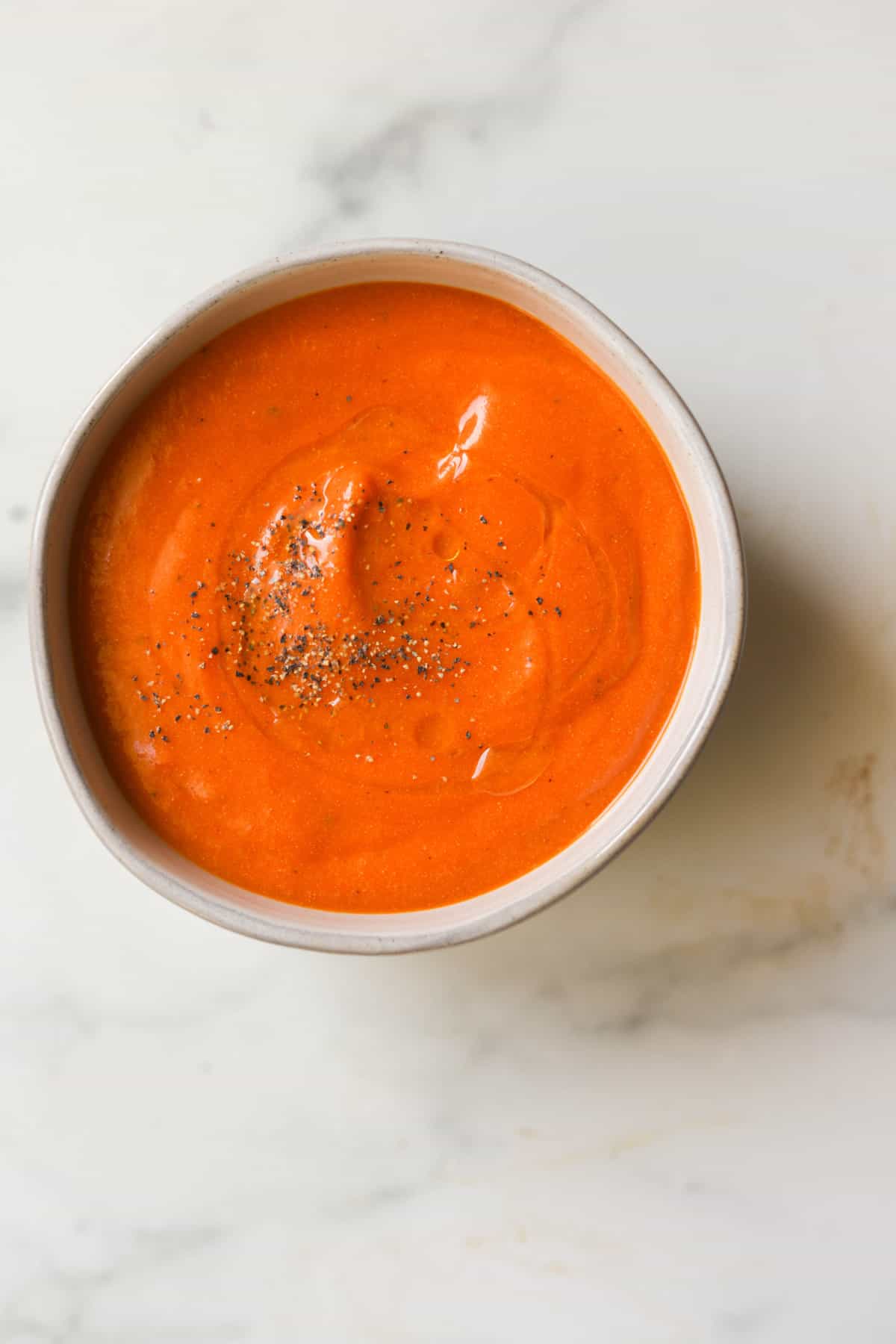 An overhead shot of a small bowl filled with creamy tomato soup.