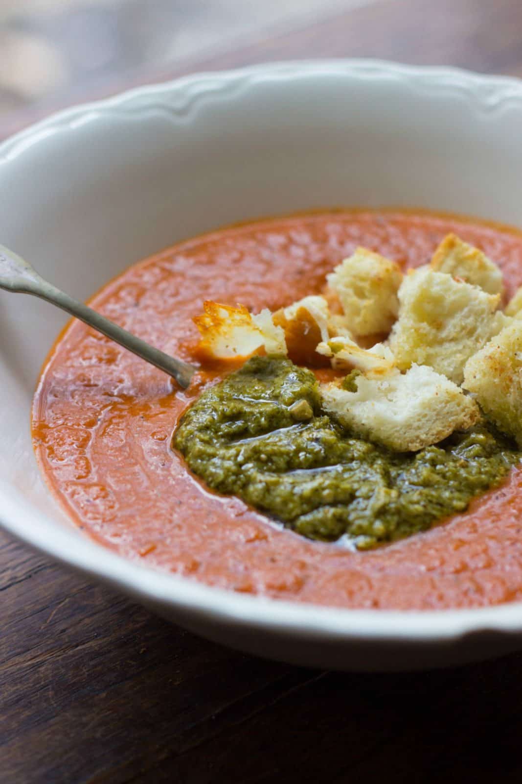 Side close-up shot of tomato soup with pesto and garlic bread croutons. 