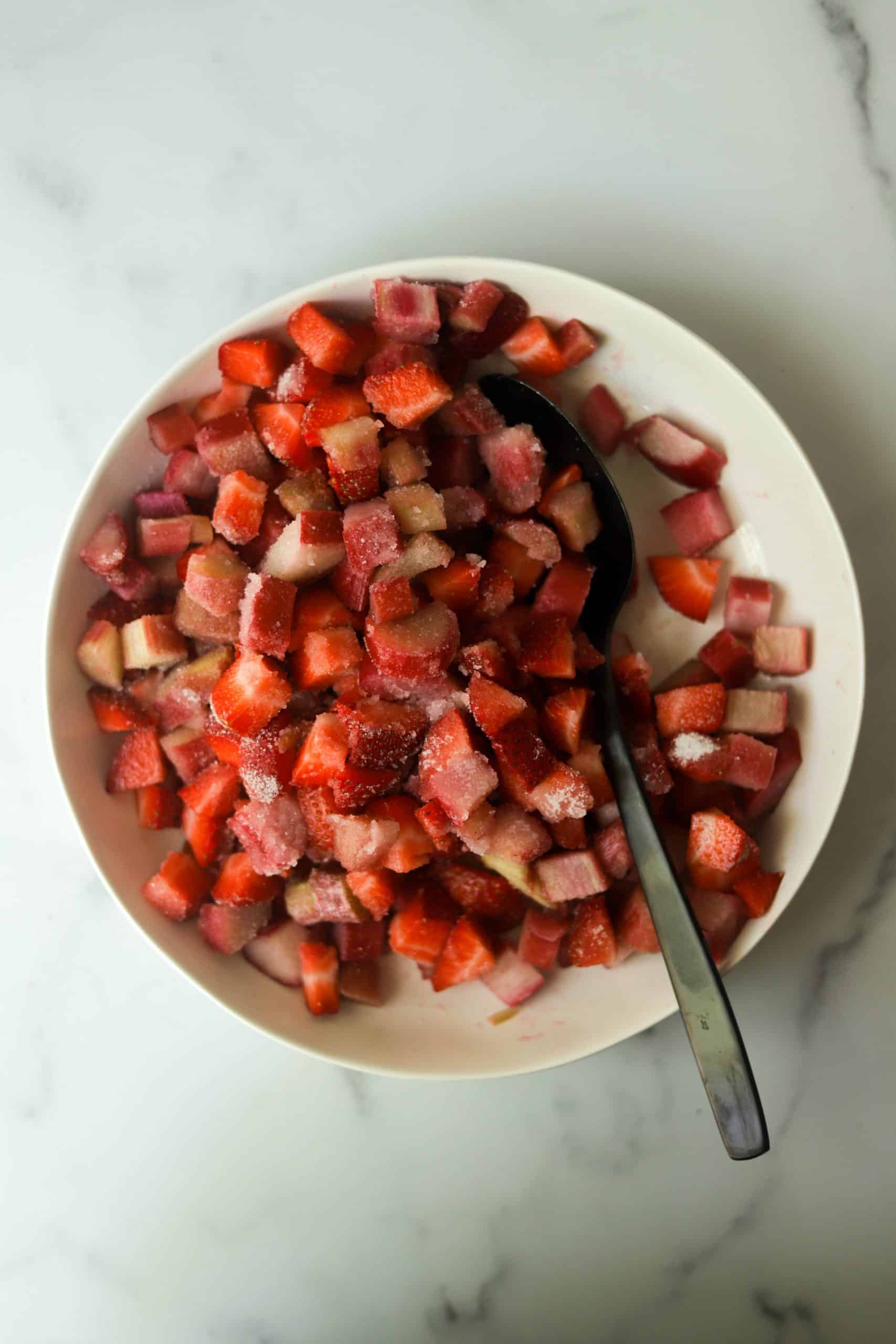 A white bowl filled with strawberries and rhubarb.