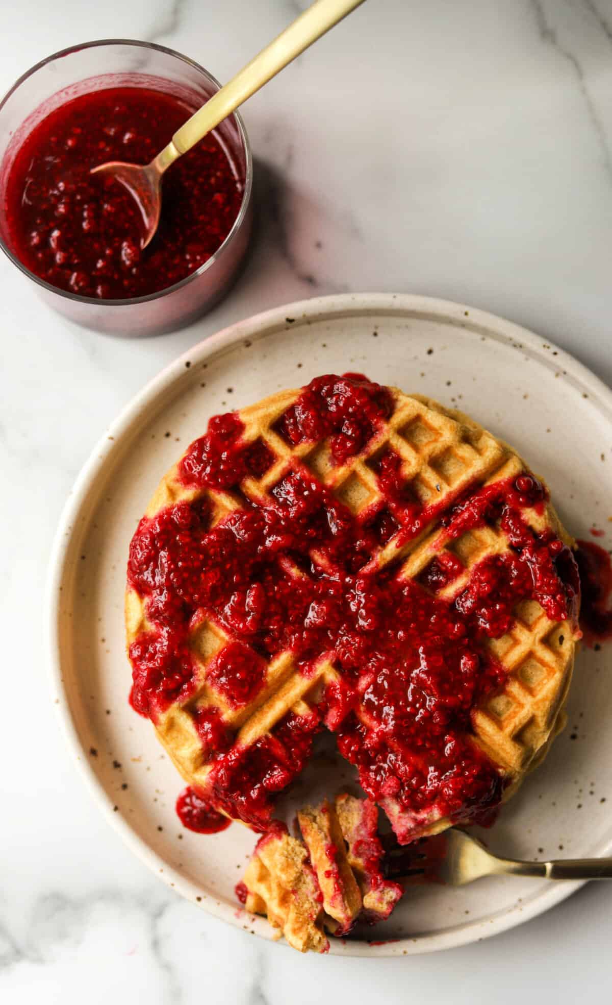 An overhead shot of lemon waffles topped with fresh berry syrup.