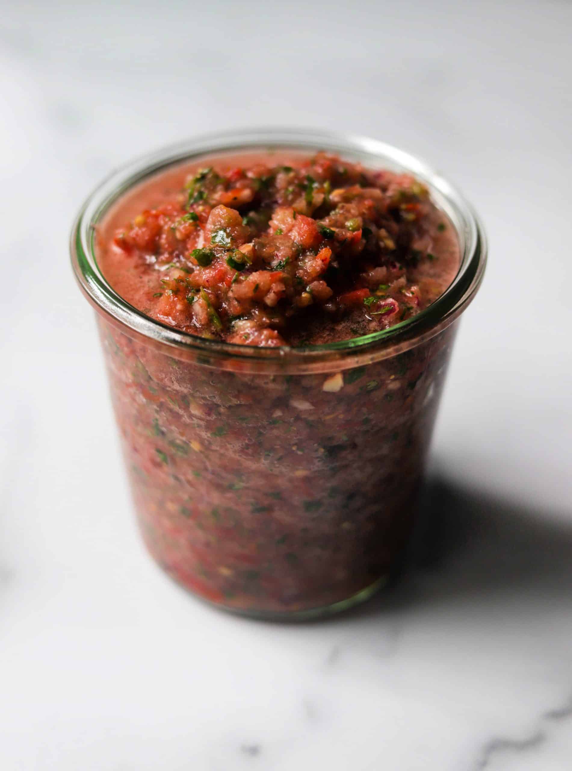 A jar filled with tomato jalapeno salsa.