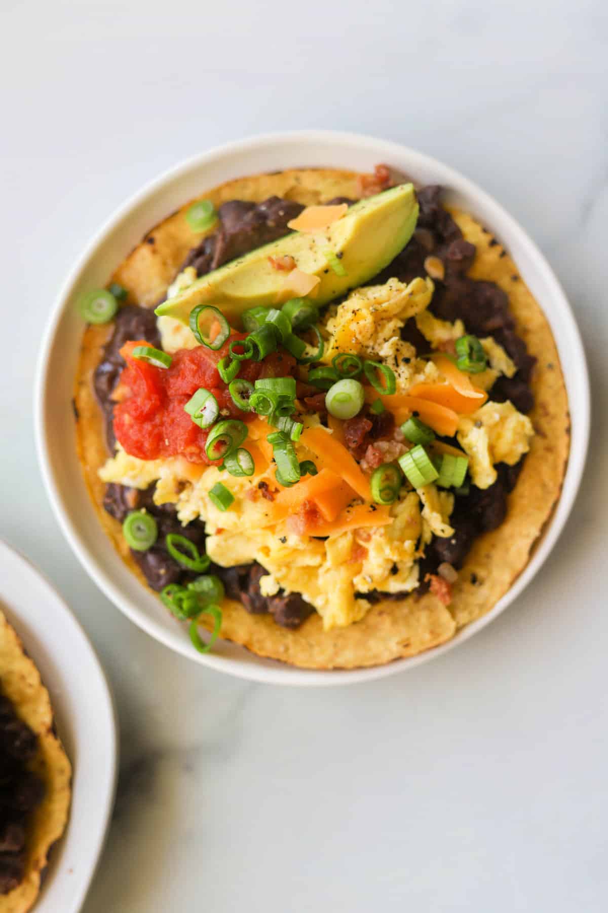 A close up overhead shot of a plate with a breakfast tostada on it.