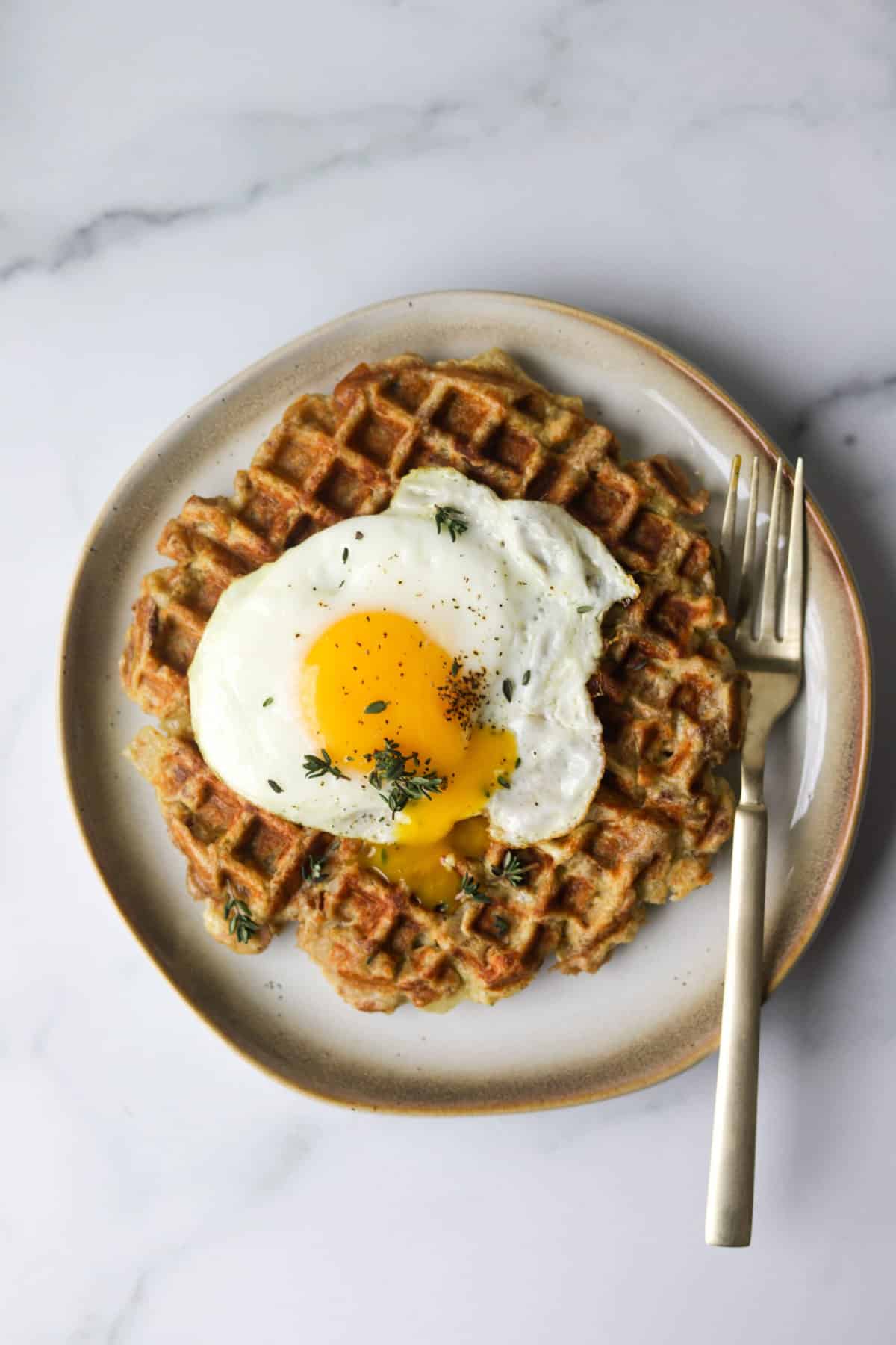 An overhead shot of a leftover stuffing waffle with a fried egg on top.