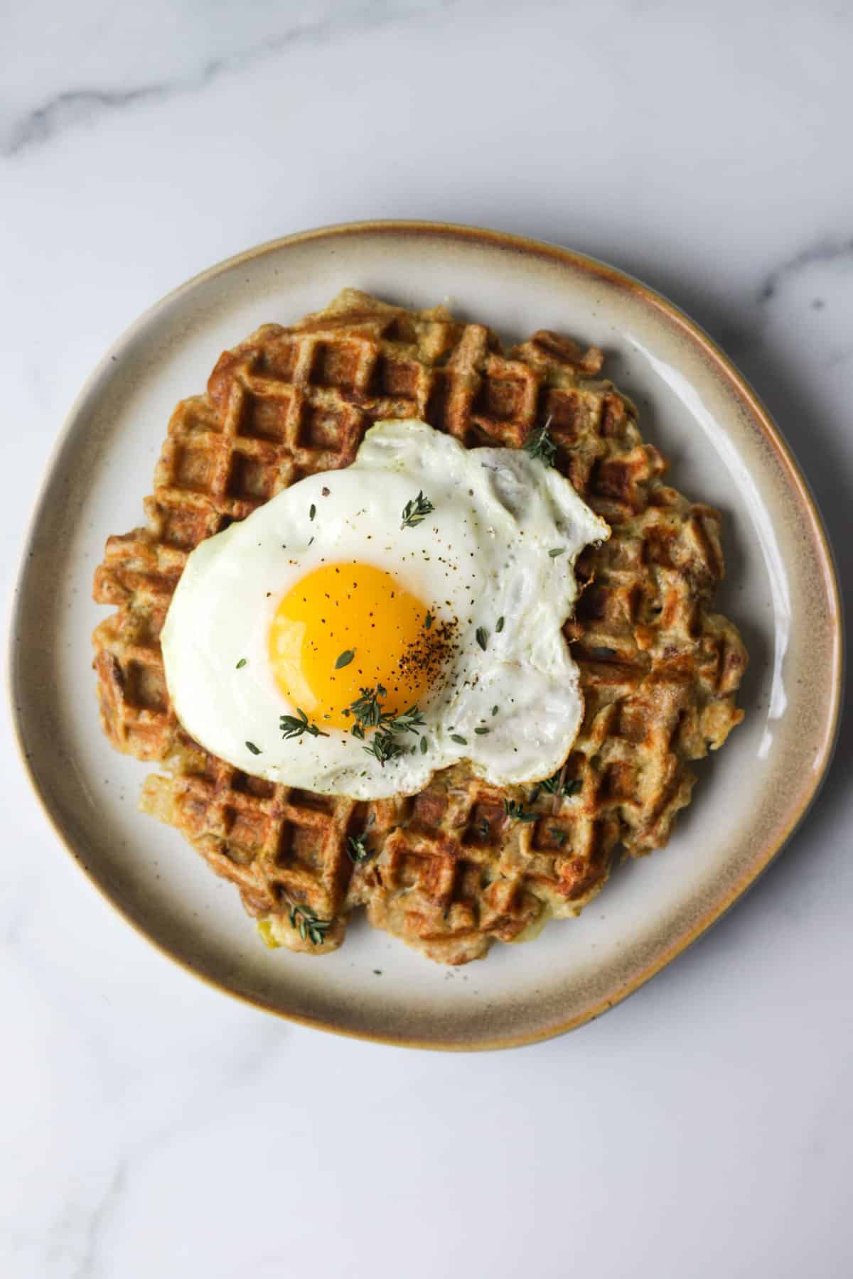 An overhead shot of a stuffing waffle topped with a fried egg.
