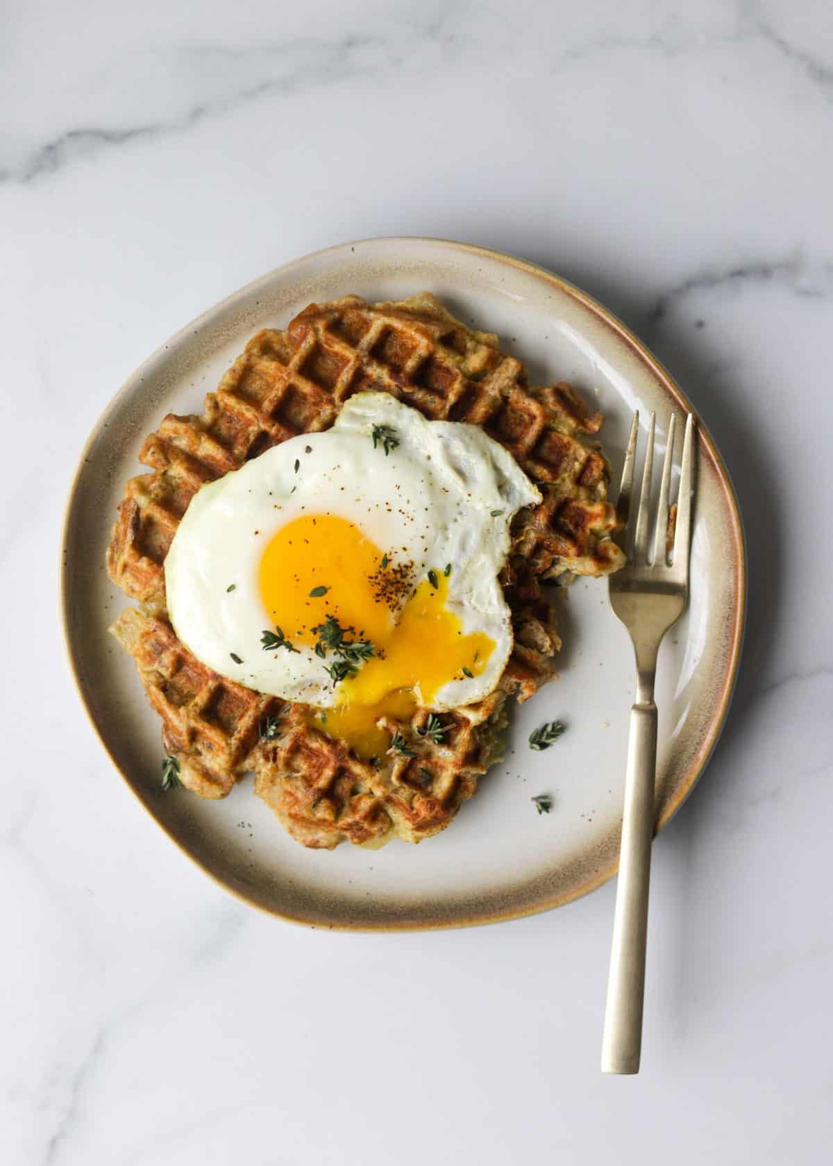 An overhead shot of a stuffing waffle with a fried egg on top.