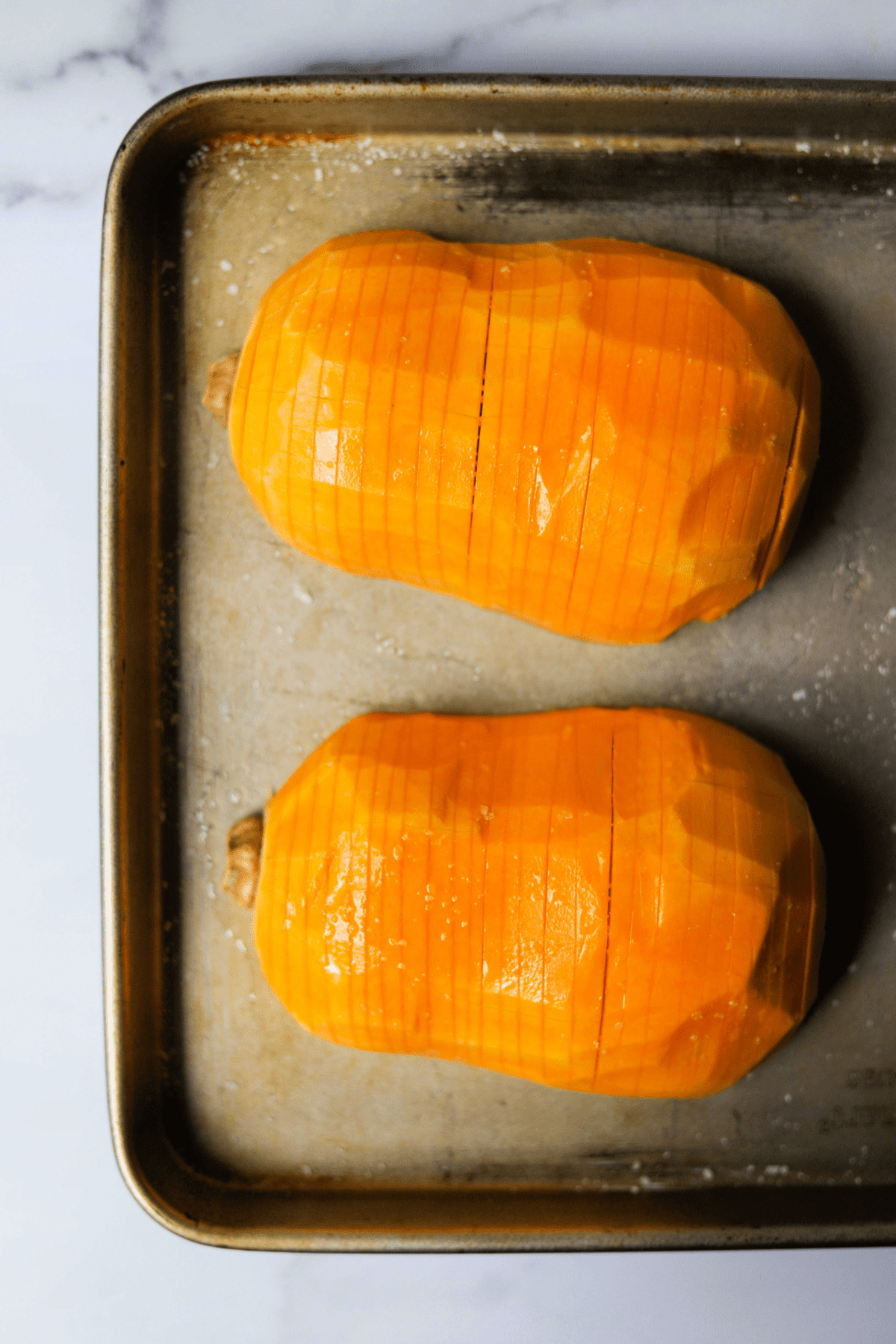 A sheet tray with sliced butternut squash on top.
