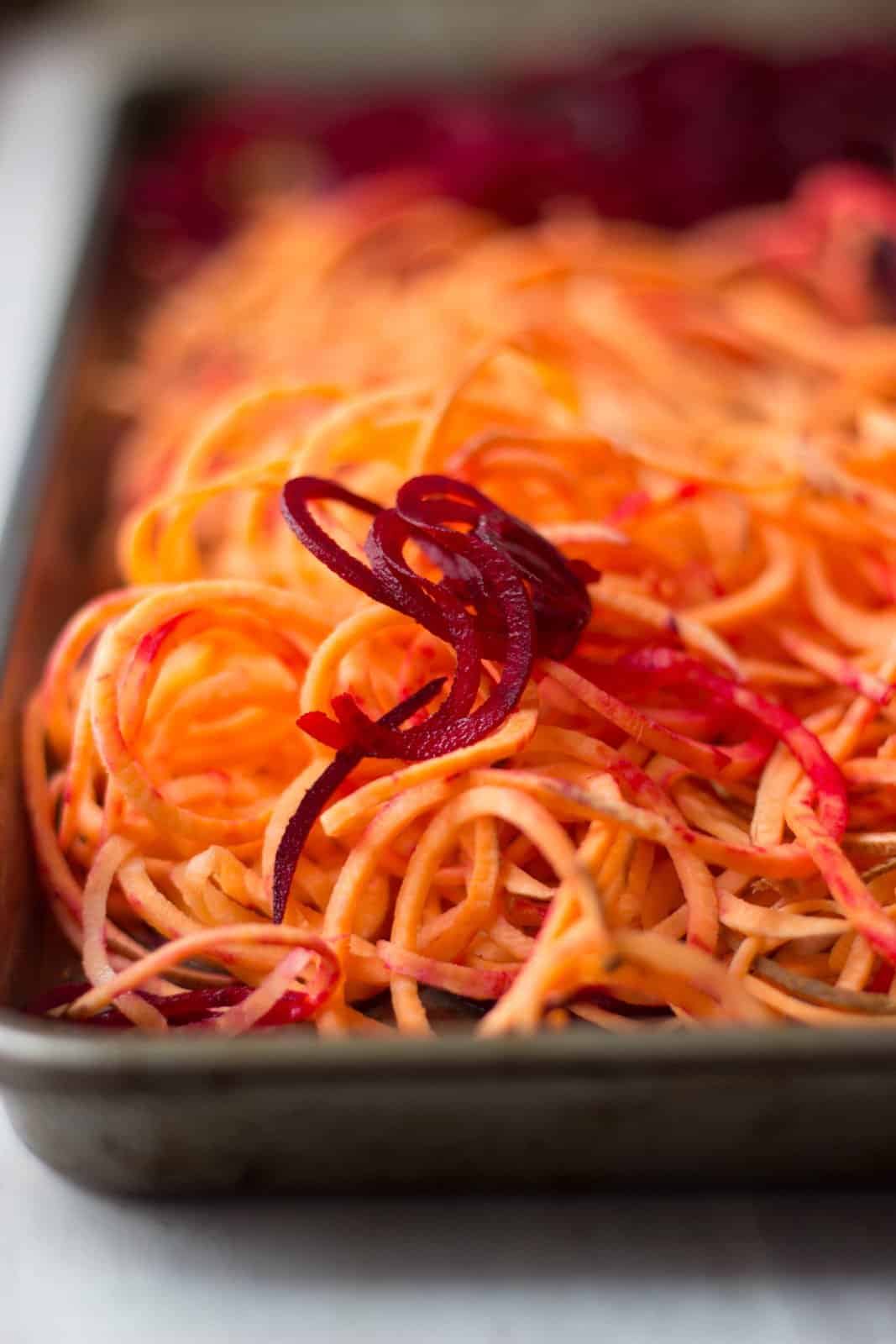Sweet potato and beet curly fries on a baking sheet