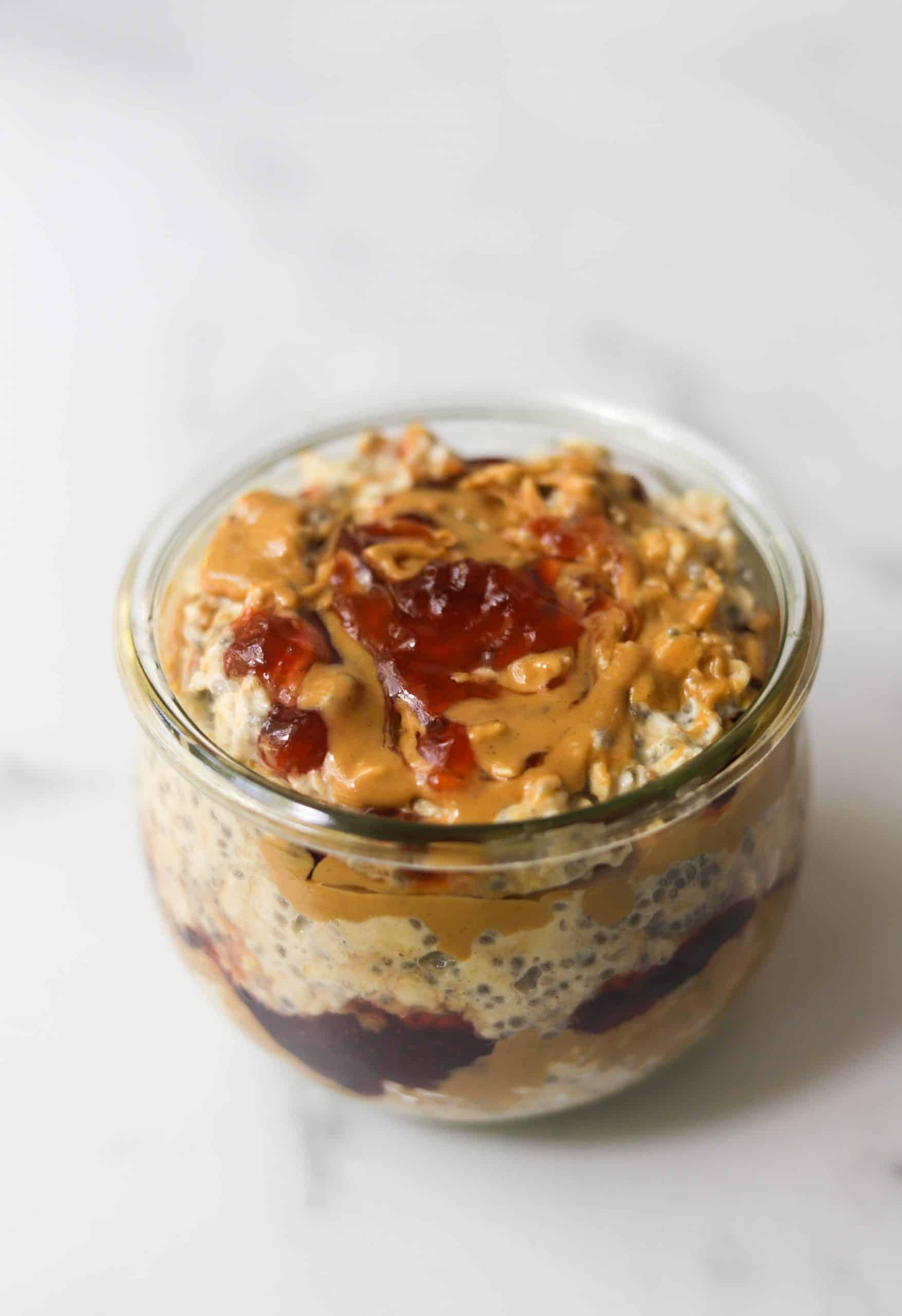 A side shot of a jar of peanut butter and jelly overnight oats.