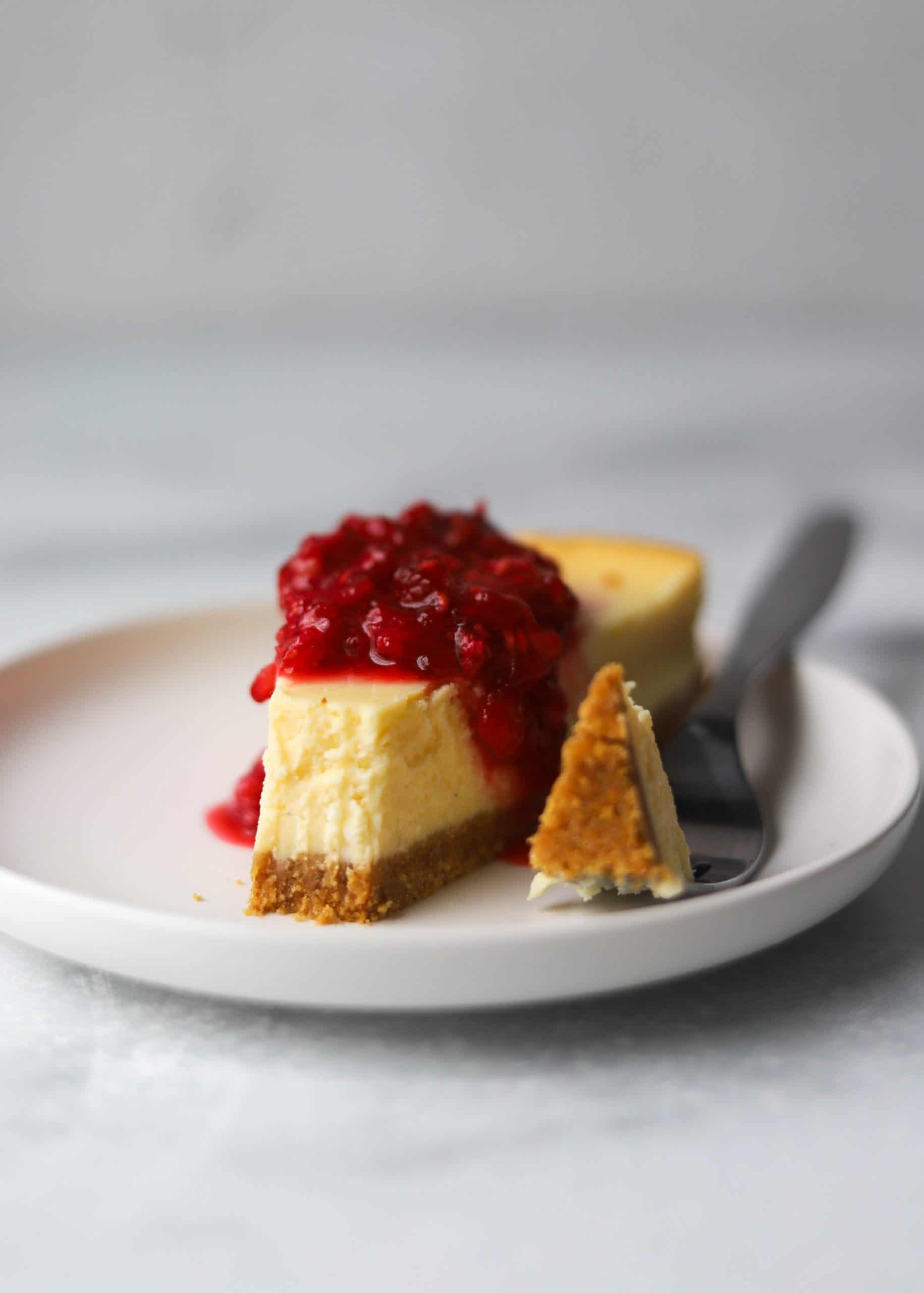 A slice of cheesecake with a bite missing on a white plate.