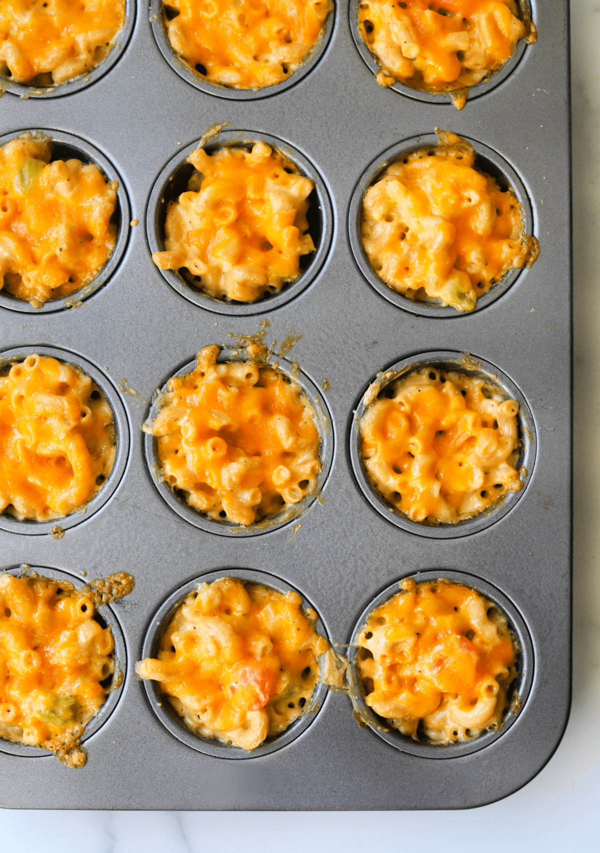 An overhead shot of mac and cheese cups in a muffin tin.