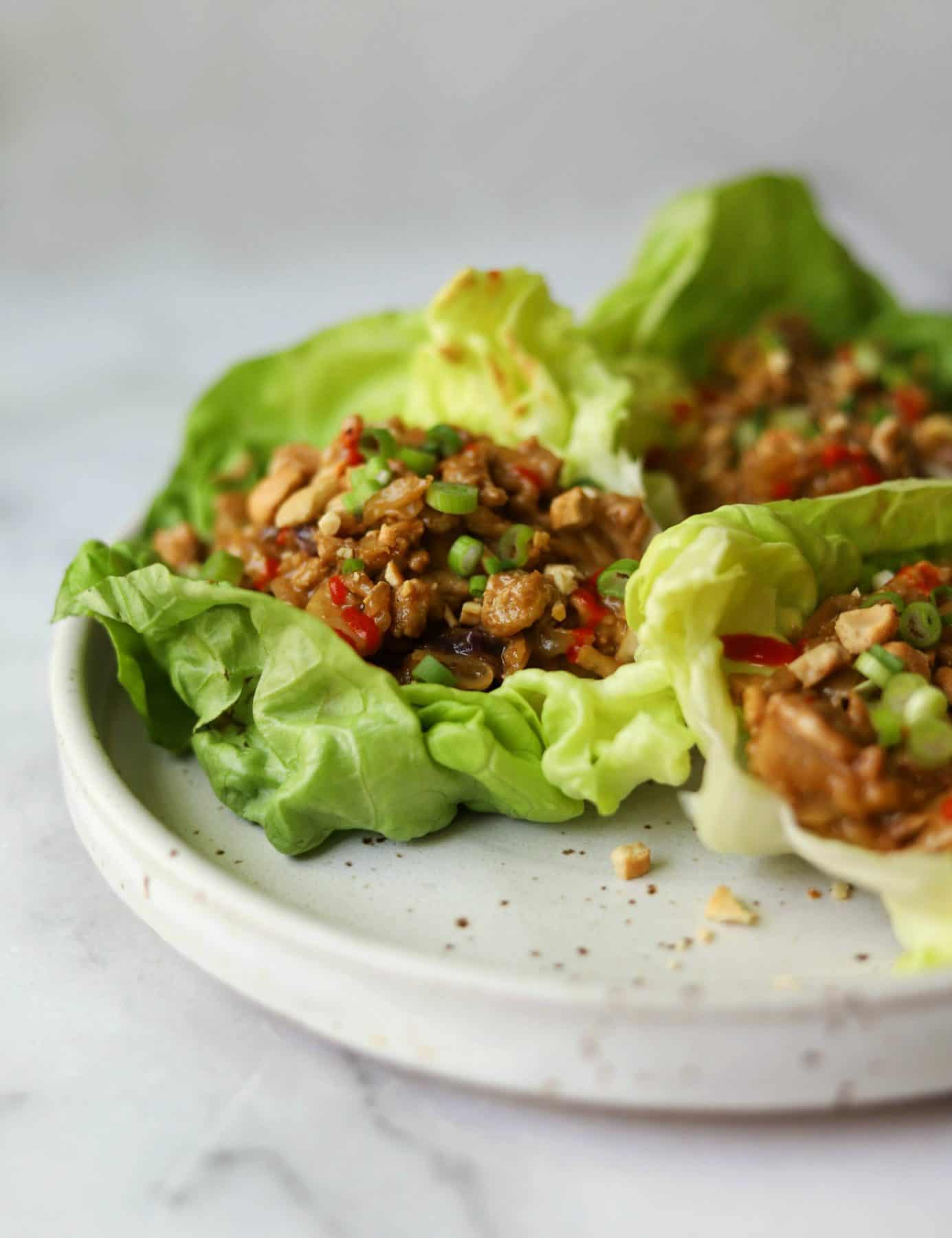 Cashew chicken lettuce wraps on a white speckled plate