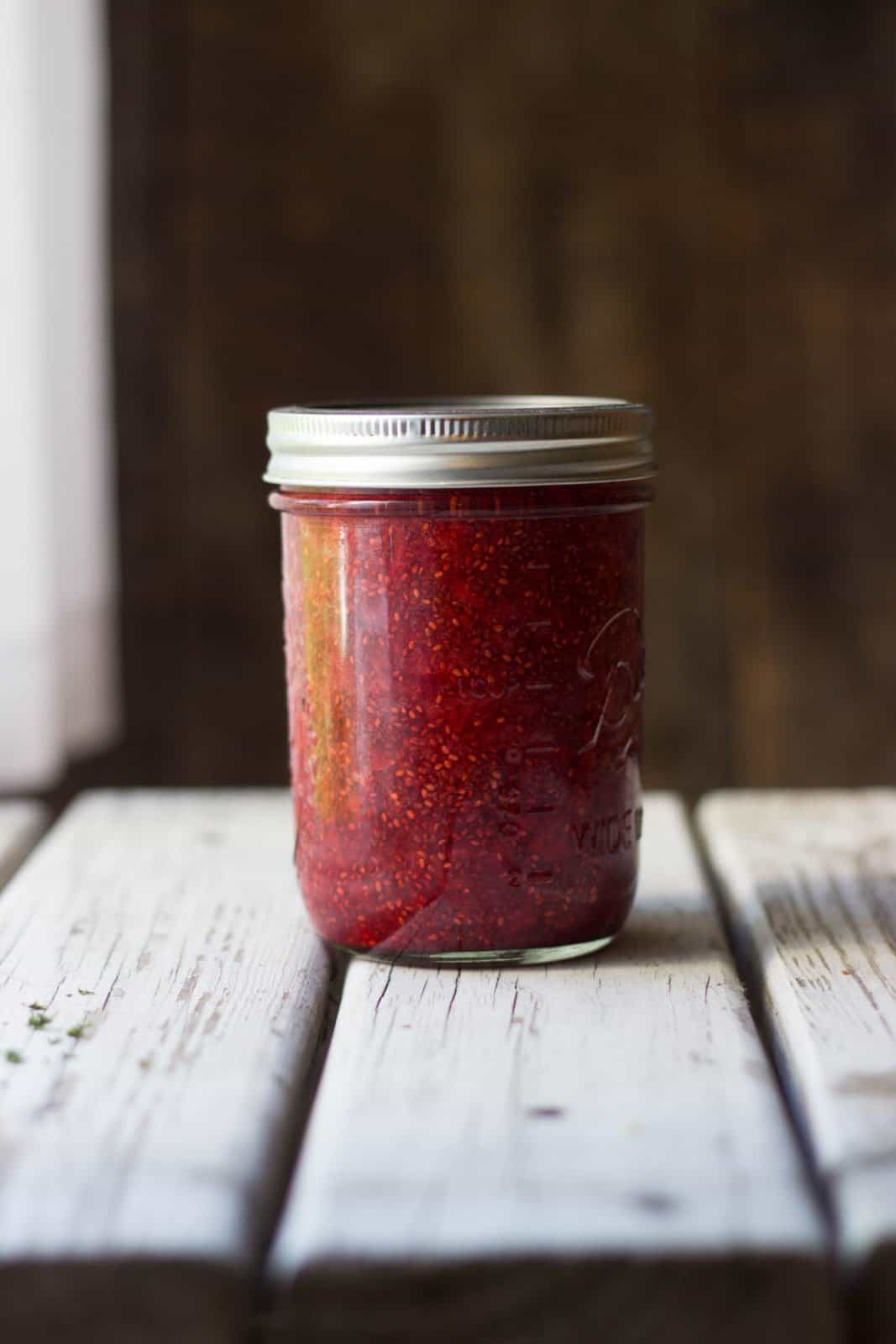 Strawberry jam in a clear mason jar with metal lid on top.
