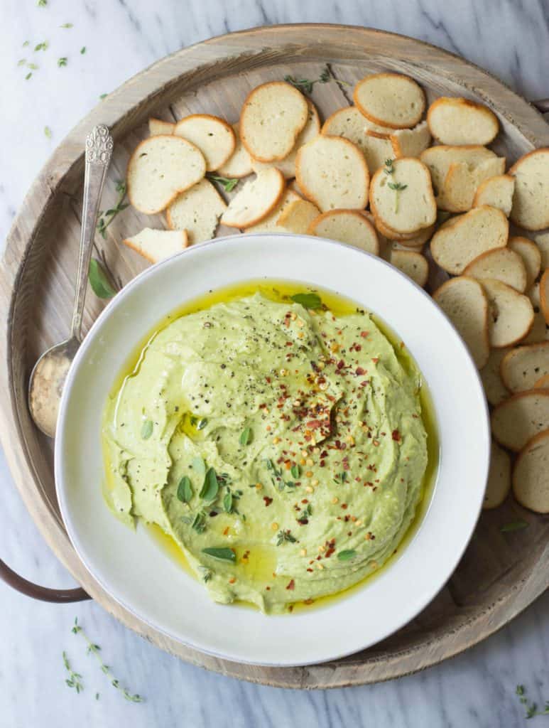 Whipped avocado white bean dip with bagel chips in a white bowl