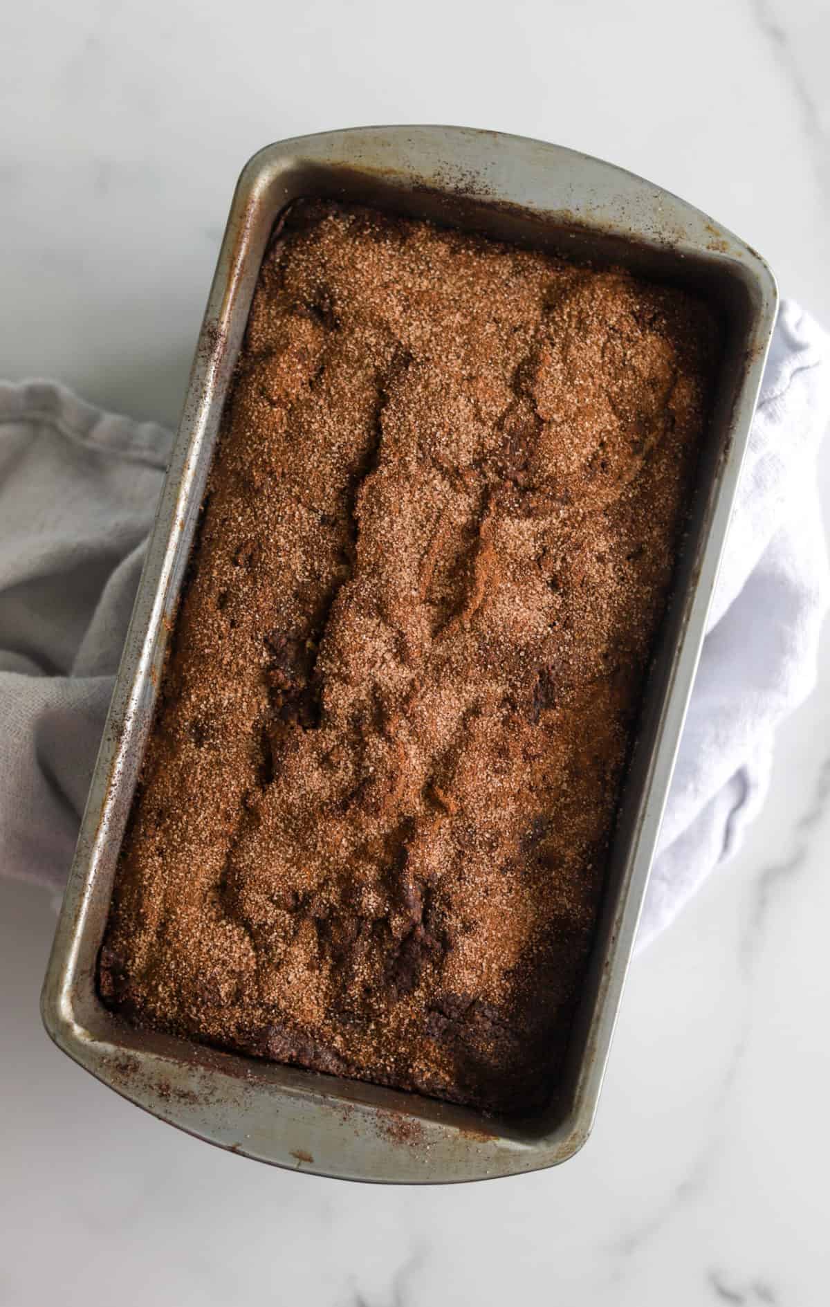 An overhead shot of a loaf of cinnamon crunch banana bread in a vintage tin.