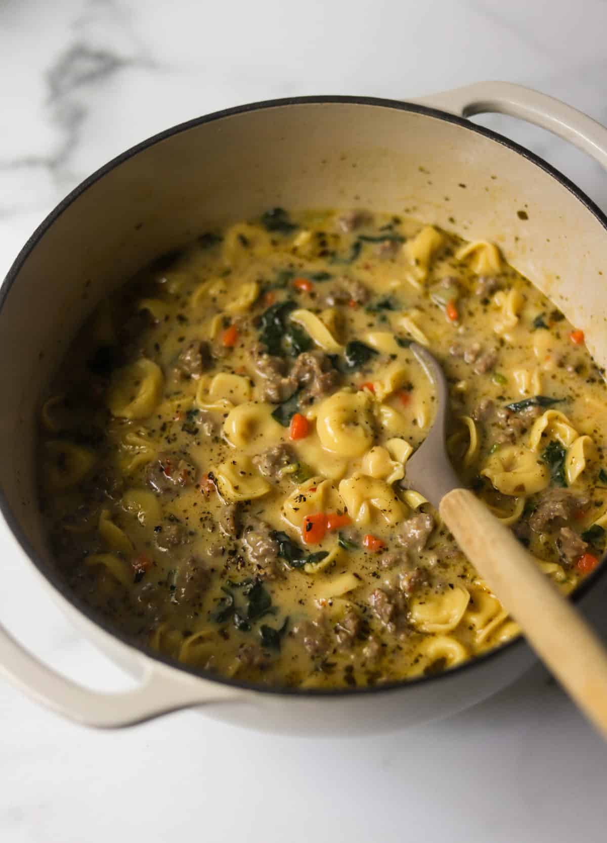 Pan of Tortellini Soup with a serving spoon.