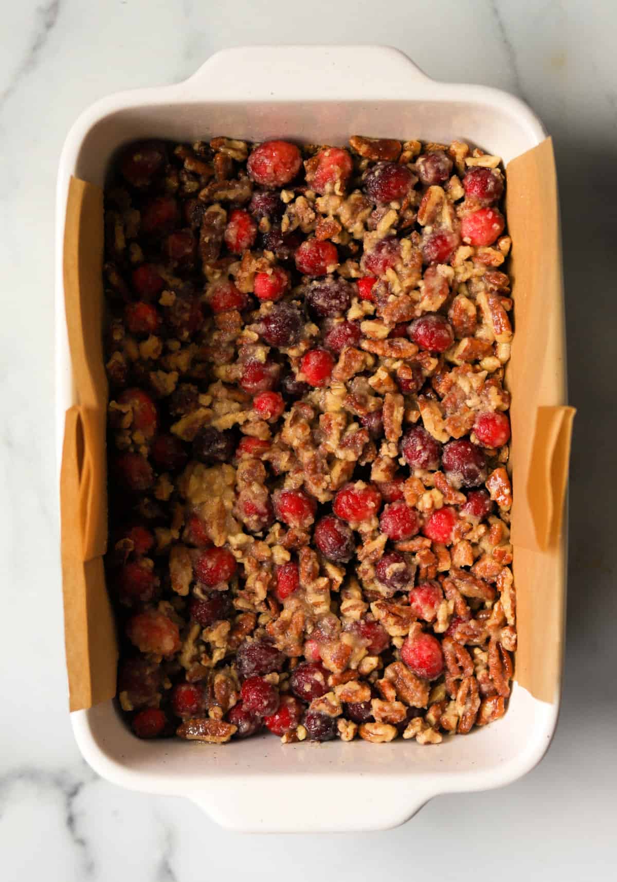 An overhead shot of a pan of cranberry pecan pie bars before baking.