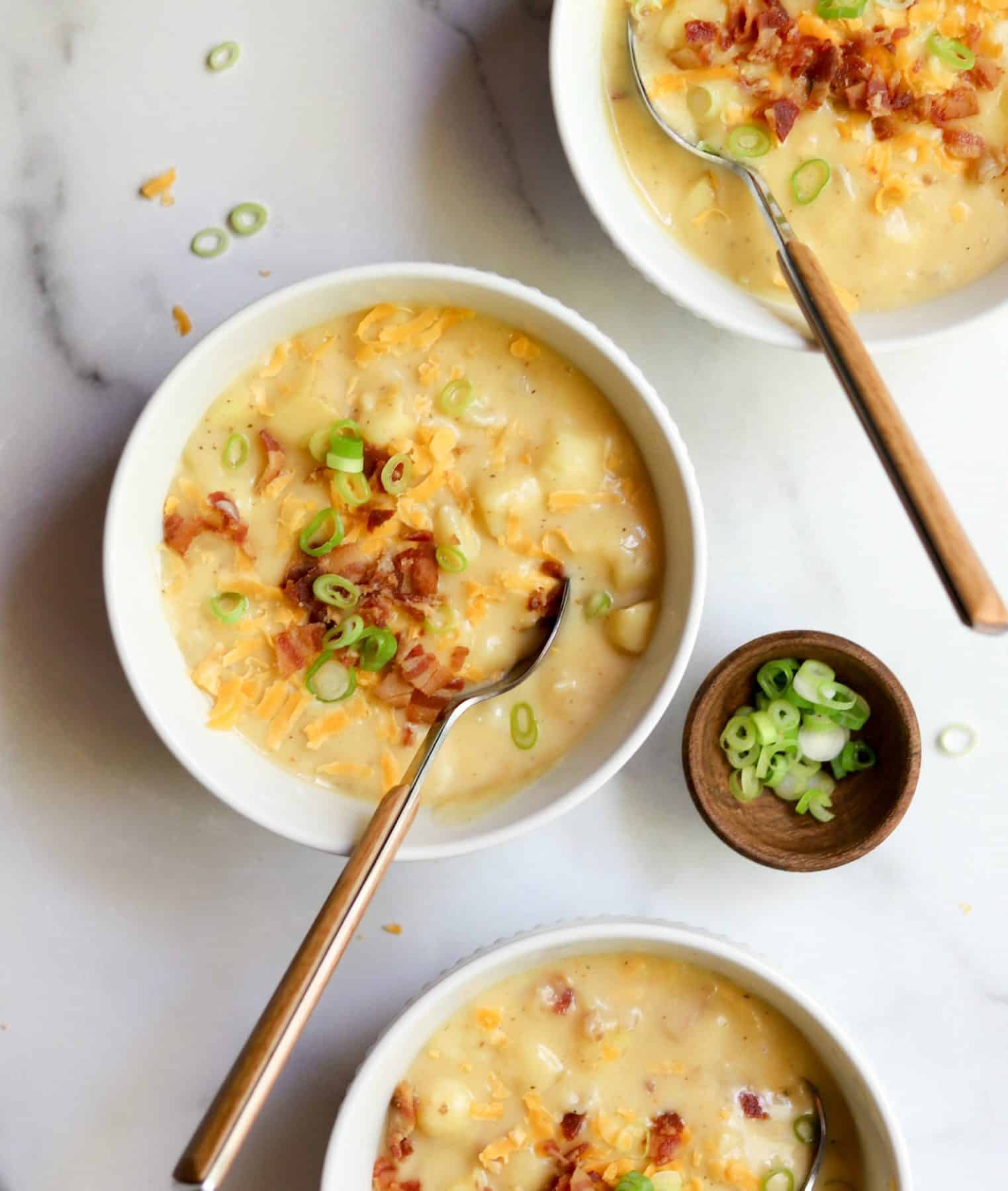 Cheesy potato soup in white bowls.