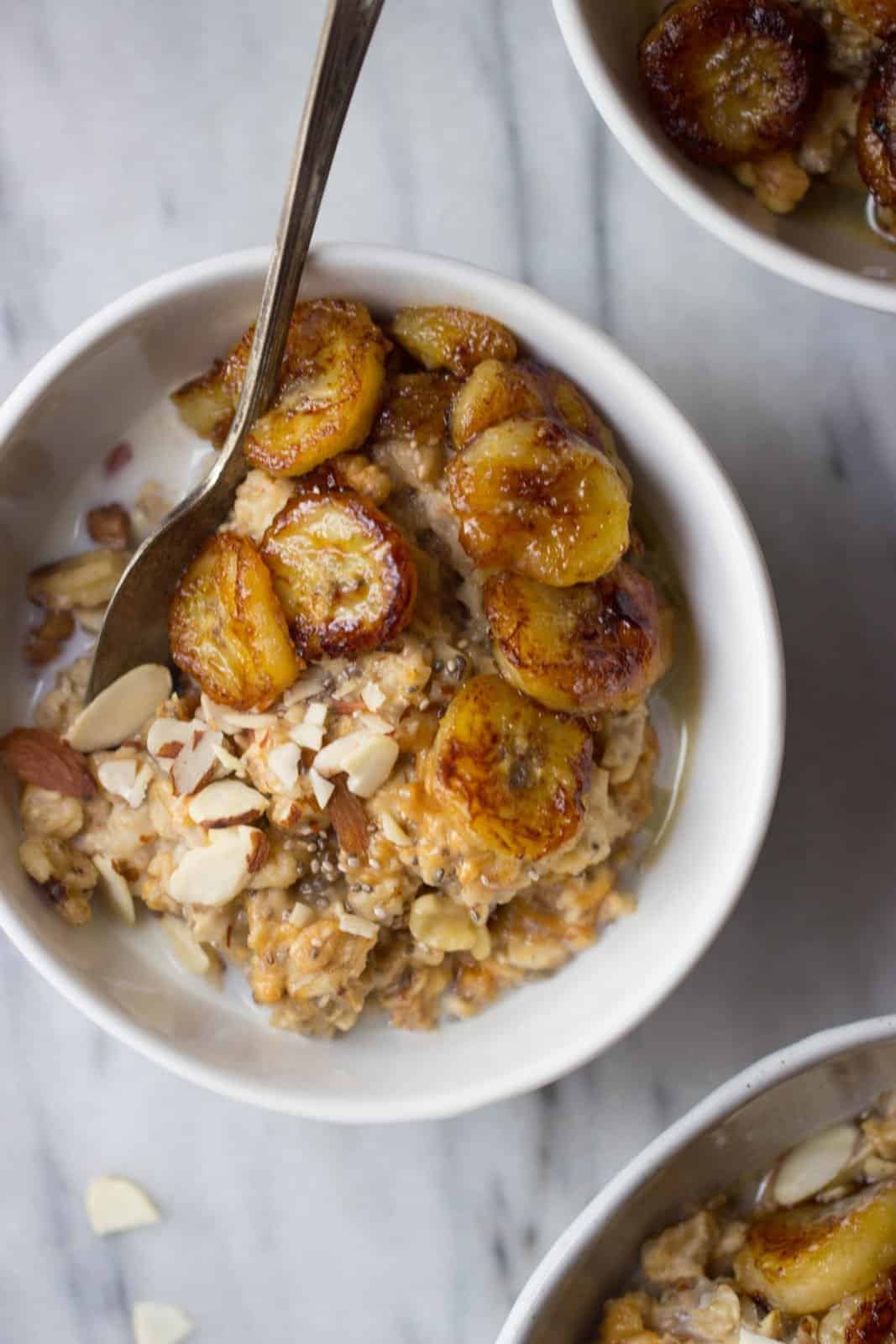 Caramelized banana and peanut butter oatmeal in a white bowl as a way to use up ripe bananas. 