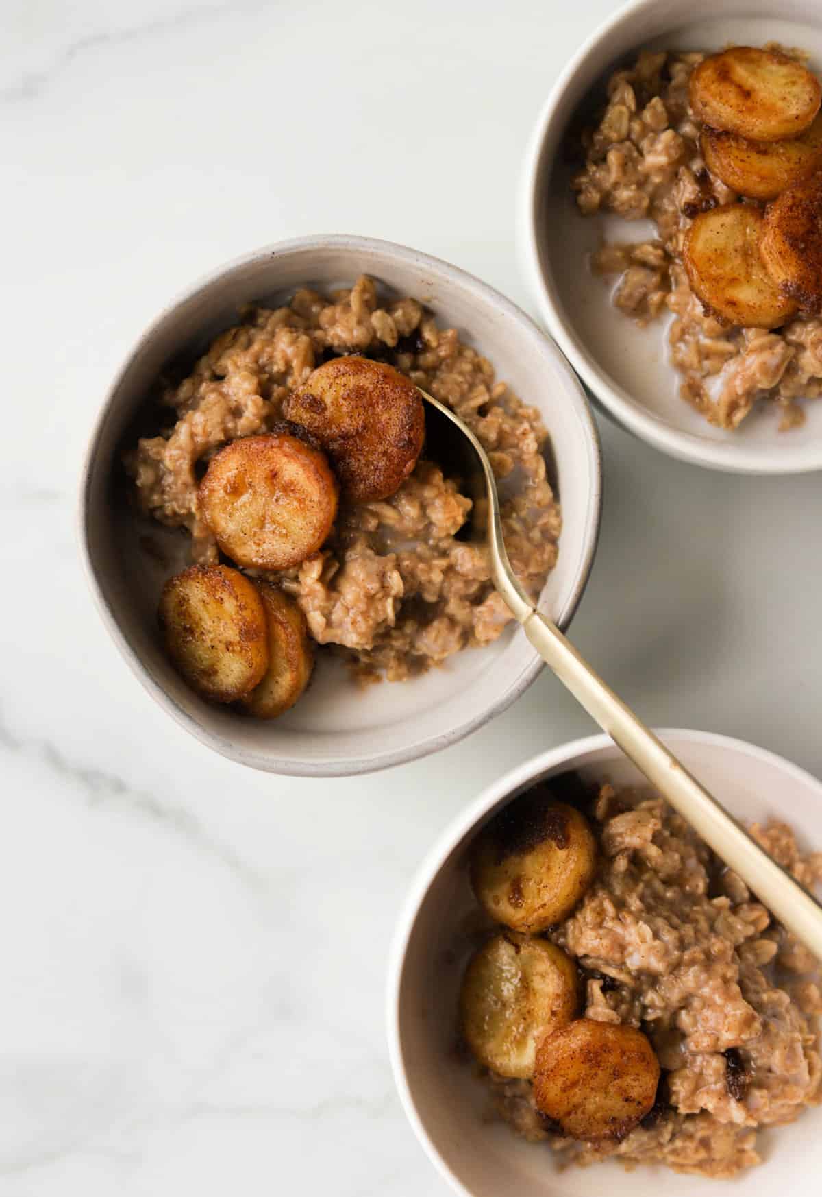 An overhead shot of bowls of peanut butter oatmeal with caramelized bananas on top.