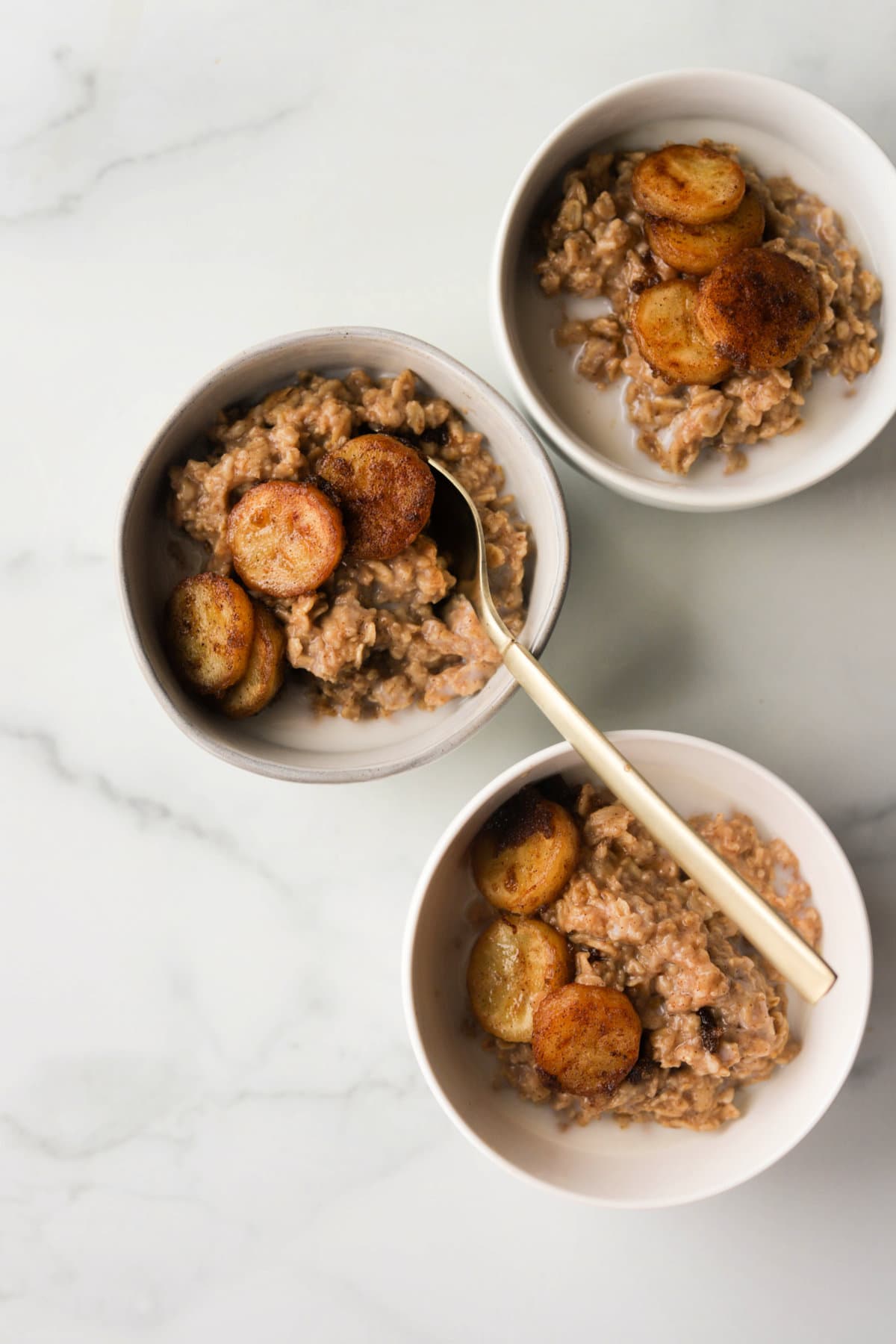 An overhead shot of three bowls of peanut butter oatmeal with caramelized bananas on top.