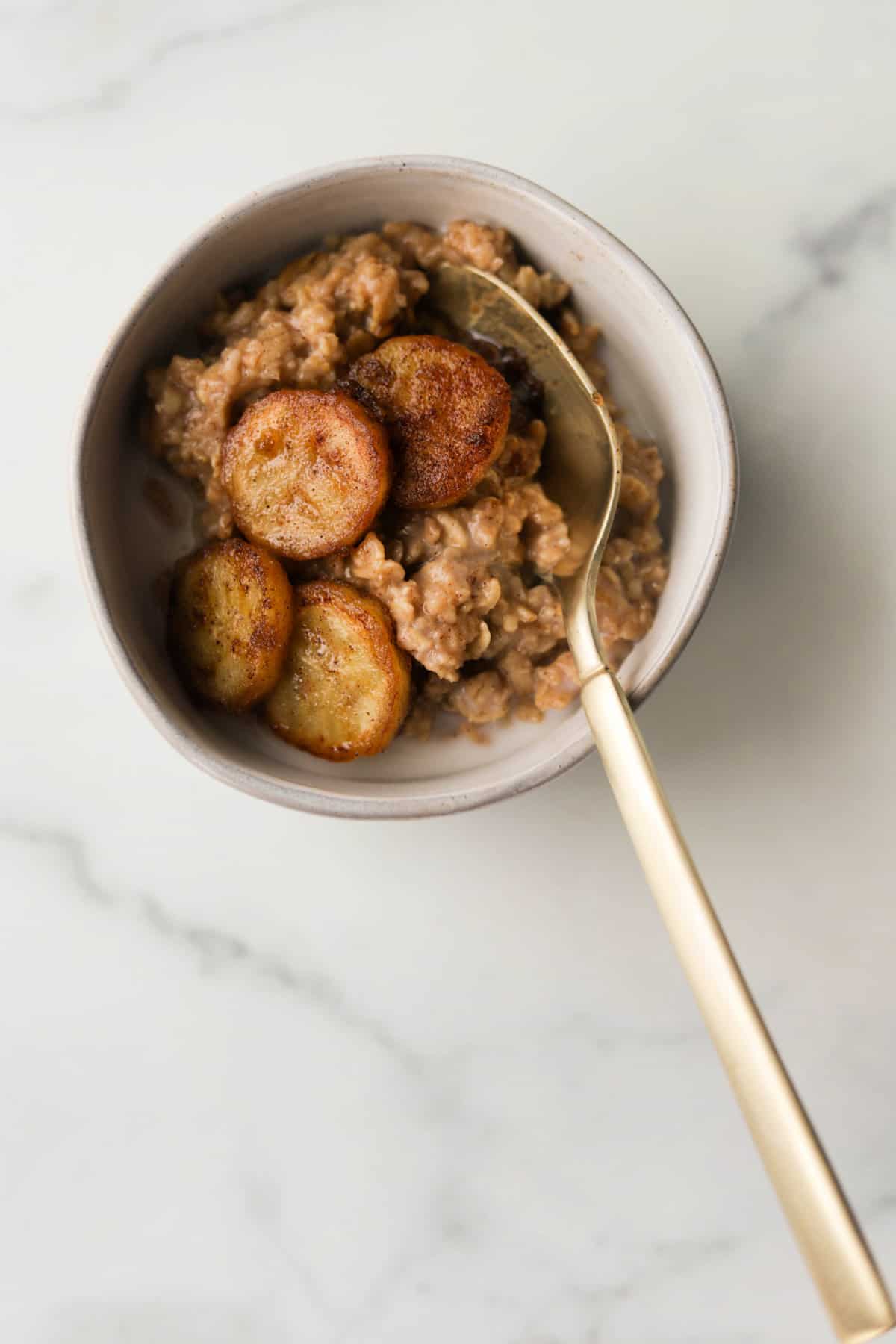 An overhead shot of a bowl of peanut butter oatmeal with caramelized bananas on top.