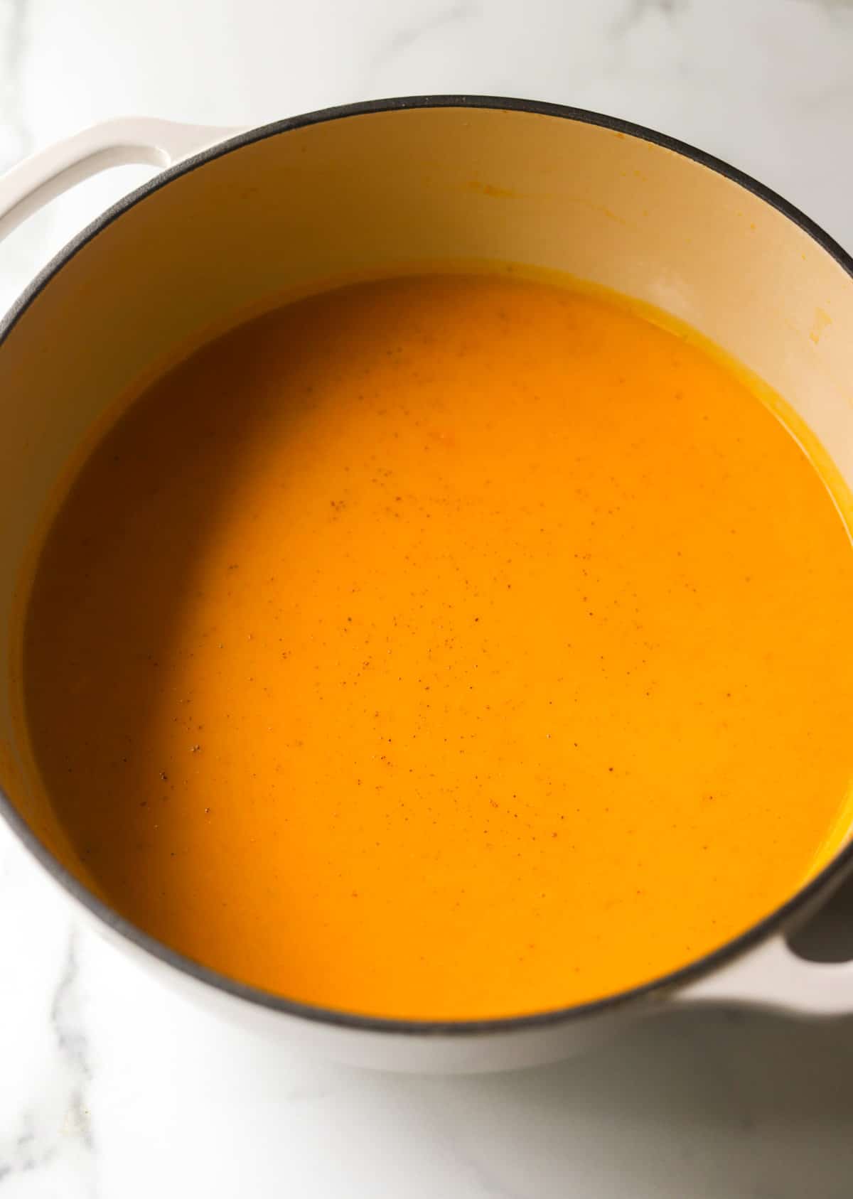 A side shot of a pot of sweet potato soup.