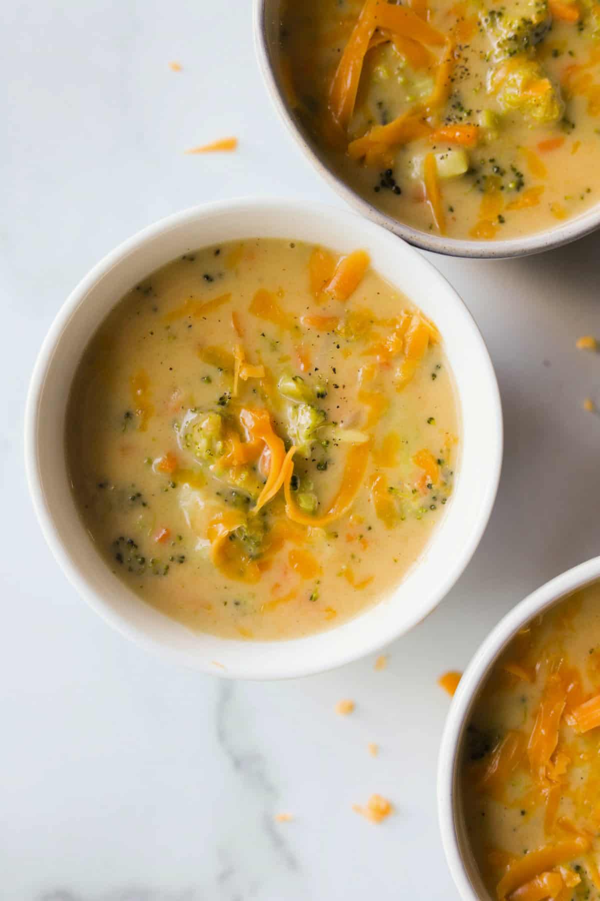 An overhead shot of bowls of broccoli cheese soup in white bowls.