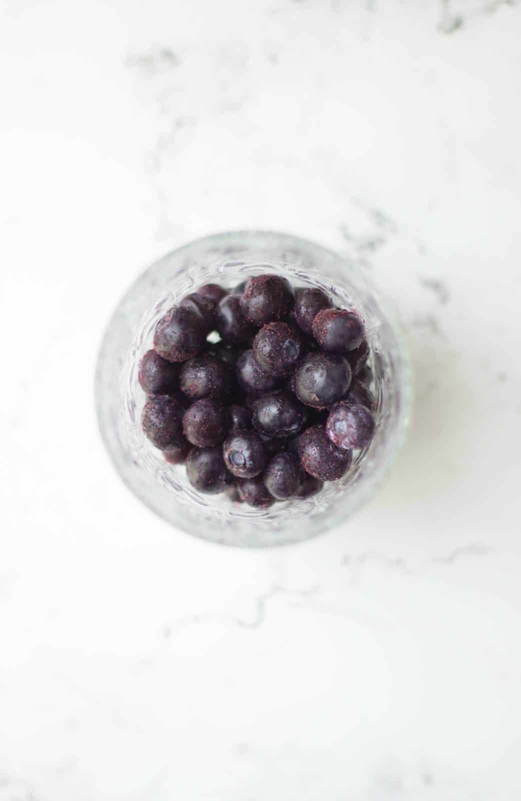 Overhead shot of blueberries in a glass bowl. 