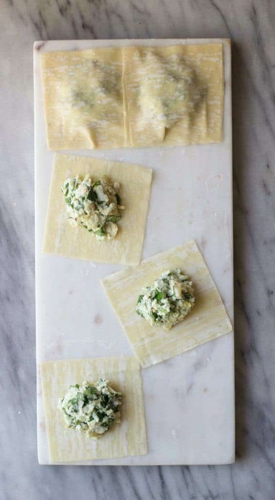 Spinach Artichoke Wonton Ravioli prior to being cooked with some open, while others are closed. 