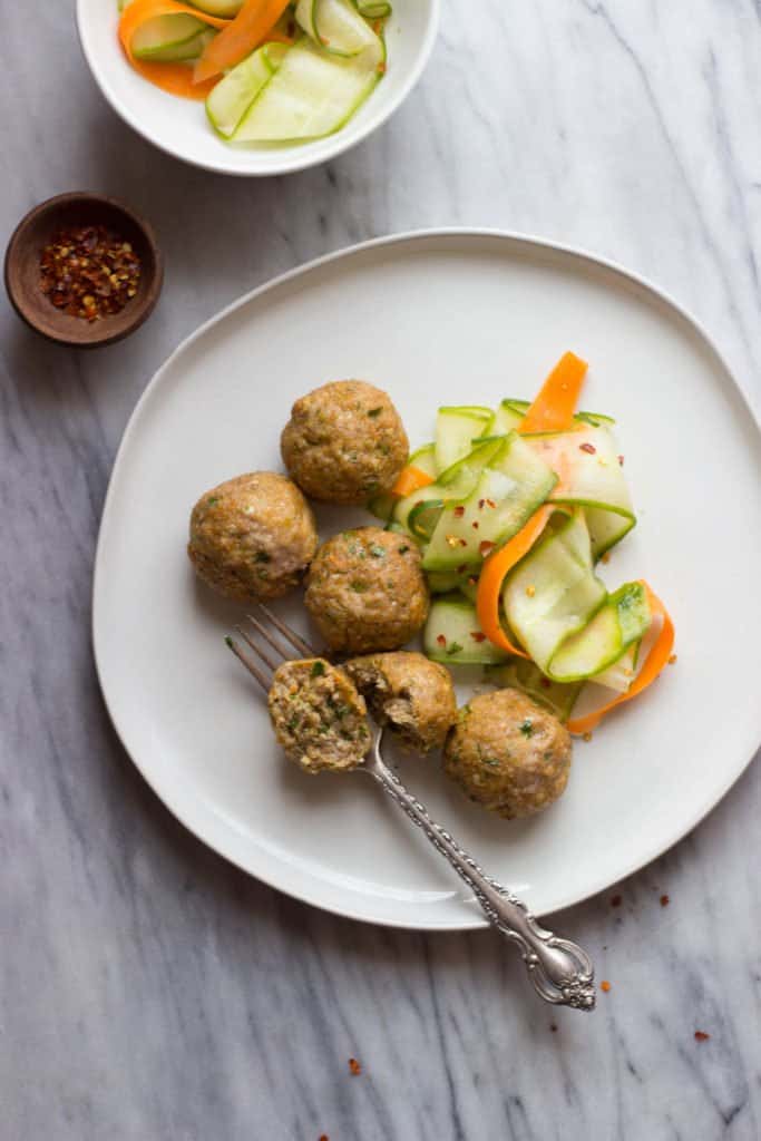 Asian-Style Pork Meatballs with Sesame Cucumber Salad with one meatball cut in half with a fork.