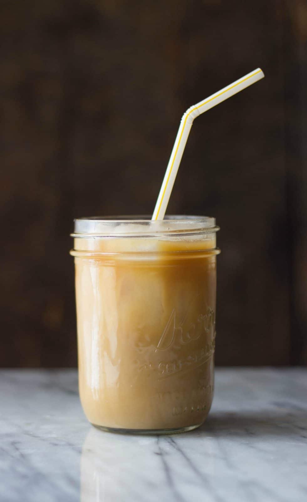 Stirred Coconut Caramel Cold Brew Coffee with a straw in a mason jar.