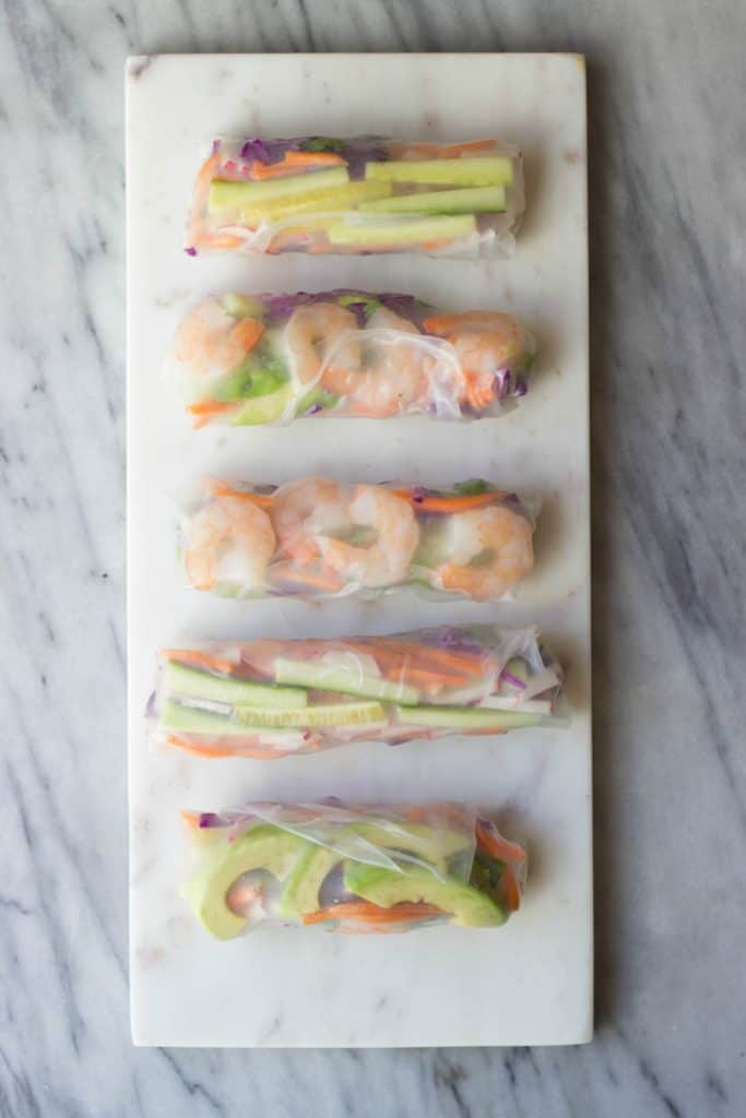 Wrapped spring rolls on a white marble board. 