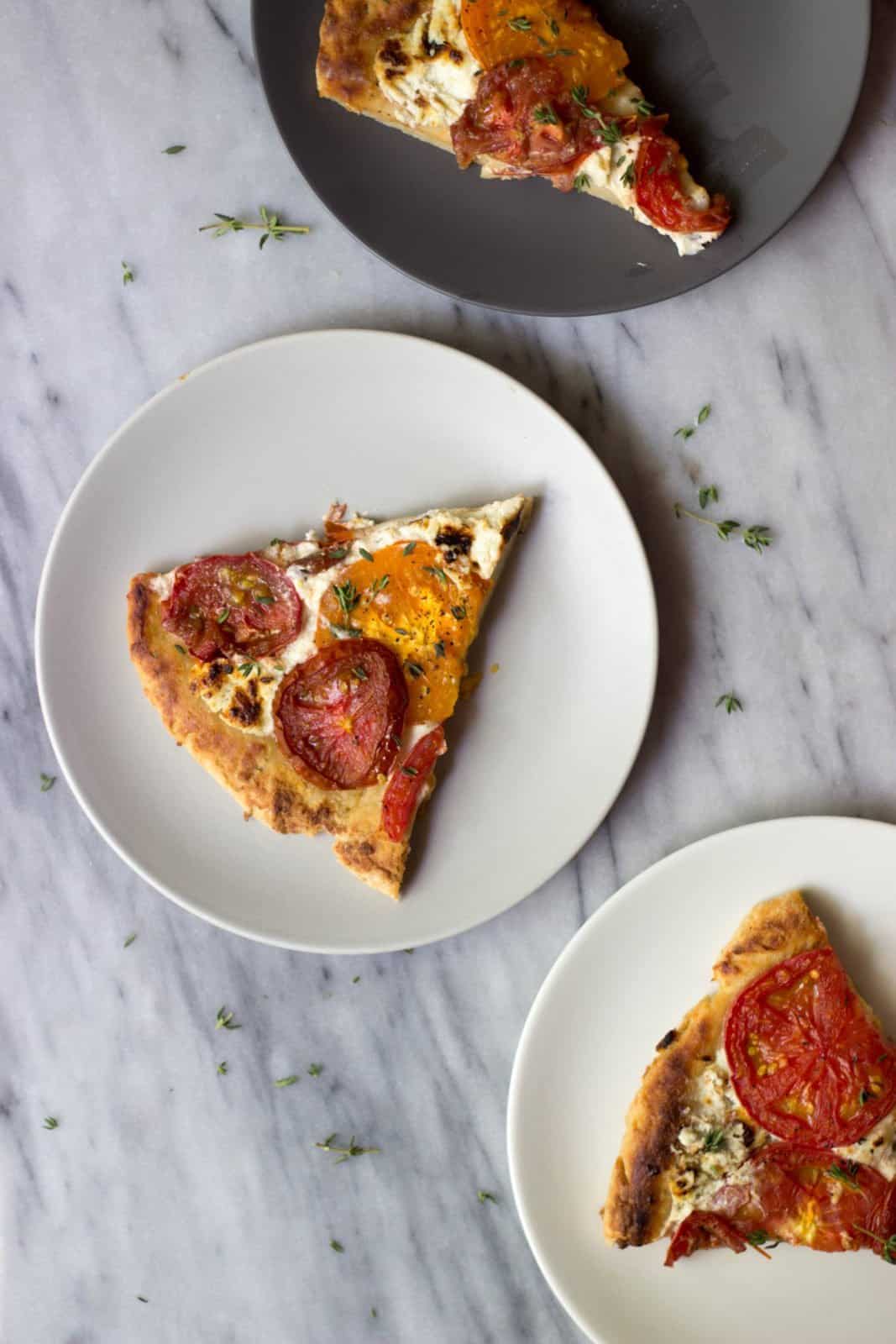 Rustic Heirloom Tomato Pizza slice on a white plate. 