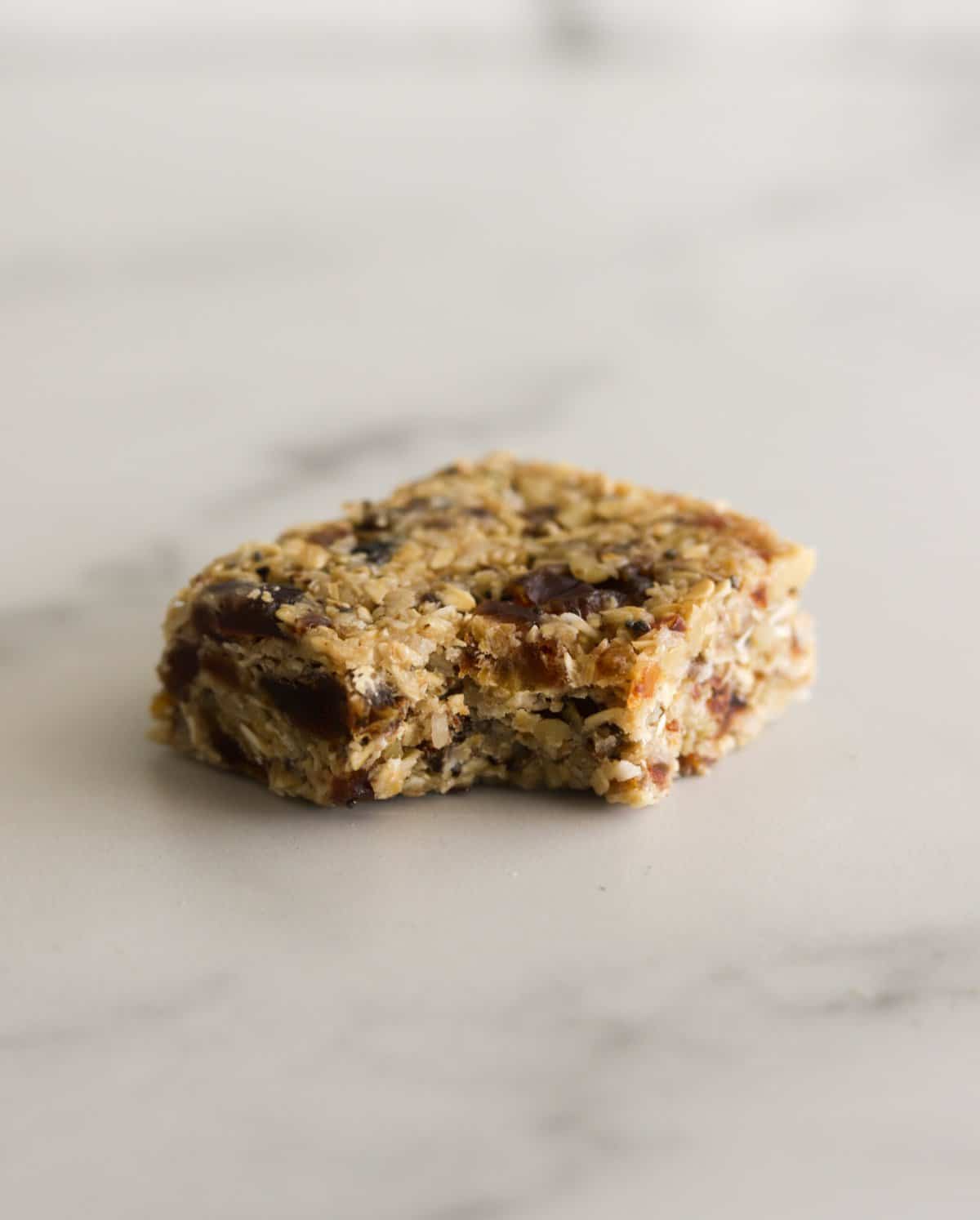 A side shot of a raw oat bar with a bite out of it.