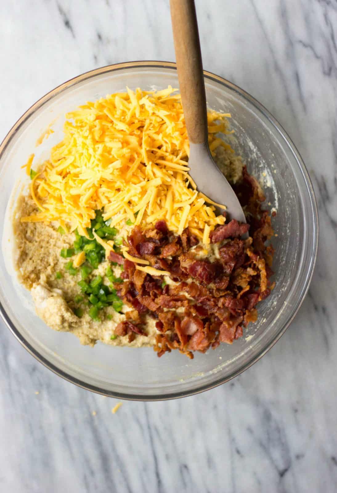Cornbread muffin batter with cheddar, bacon and jalapeno in a bowl.