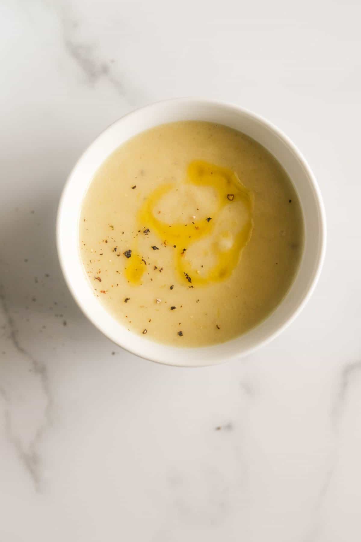 An overhead shot of a single bowl of potato leek soup.