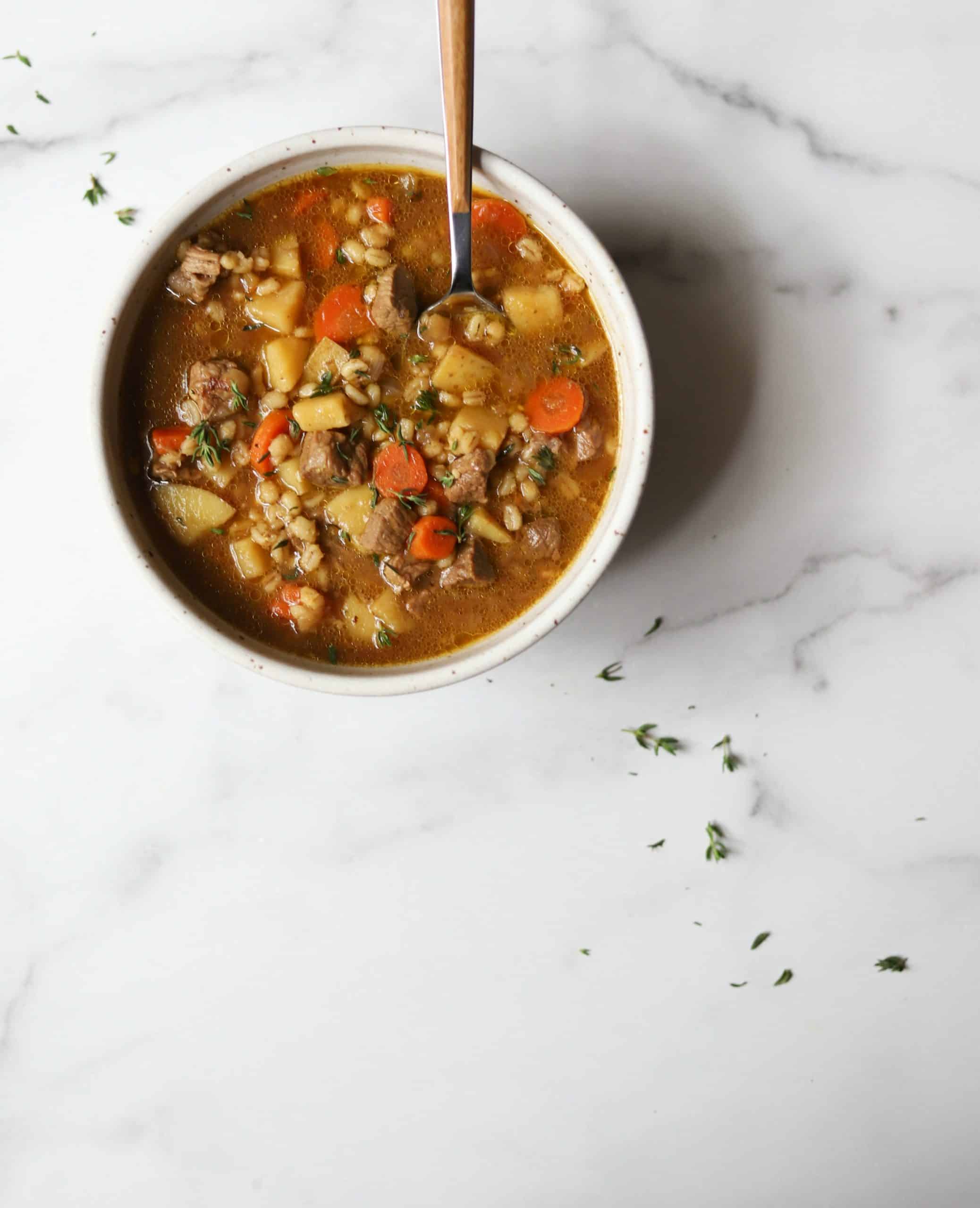 Beef barley soup in a white bowl