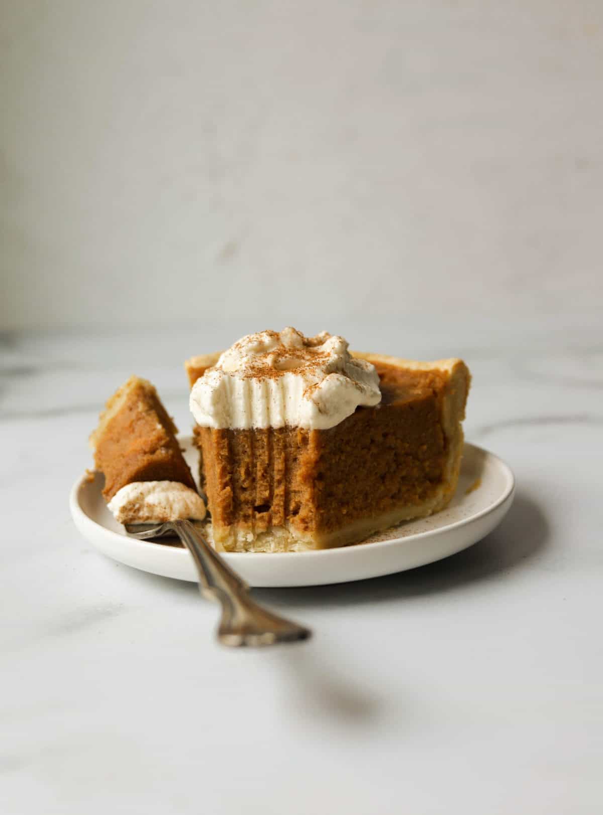 A side shot of a slice of sweet potato pie with a bite missing.