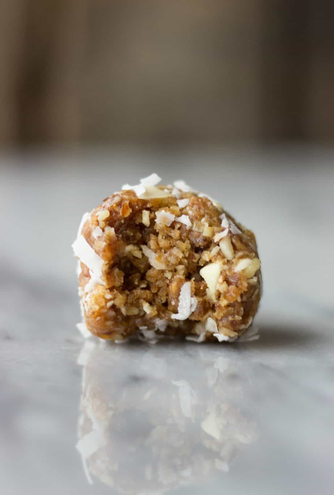 Close-up shot of one Coconut Date Energy Bite with a bite taken out of it