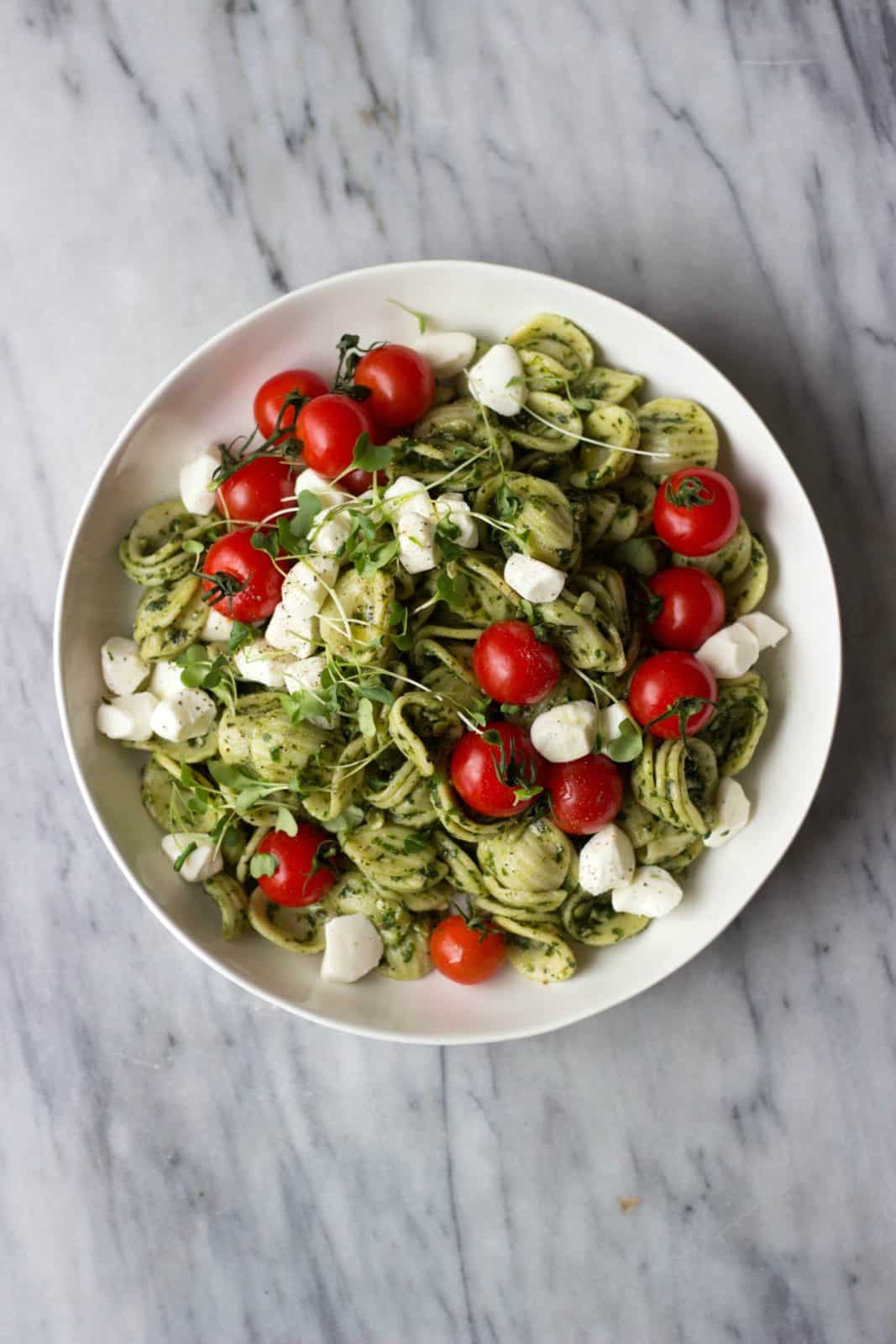 Overhead shot of finished Caprese Pasta Salad recipe in a white bowl. 