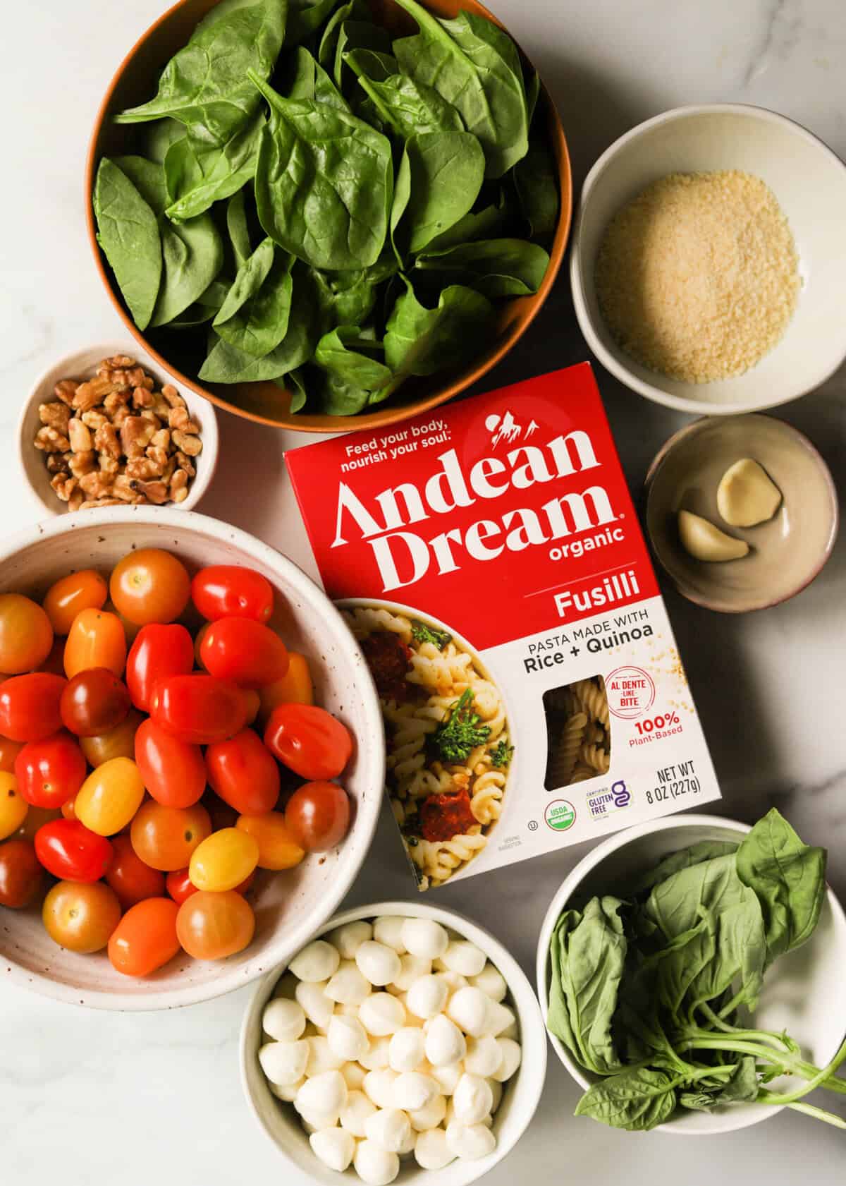An overhead shot of ingredients for caprese pesto pasta salad.