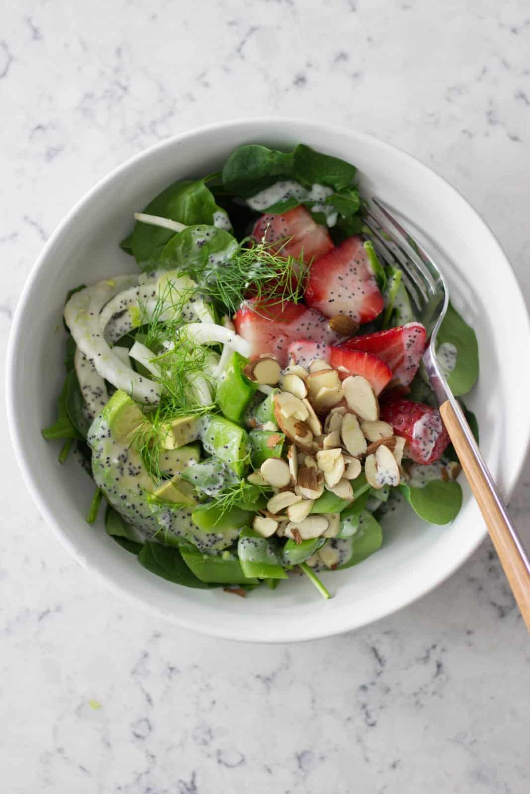 Overhead shot of almond strawberry salad with fennel in a white bowl